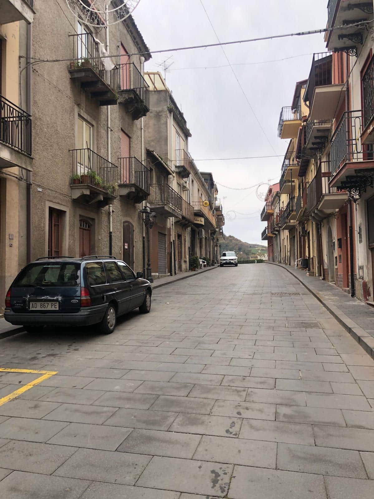 Vecchia strada di montagna con edifici residenziali e auto parcheggiate, atmosfera autentica di quartiere storico italiano, ideale per investimenti immobiliari e case in vendita NextCasa.