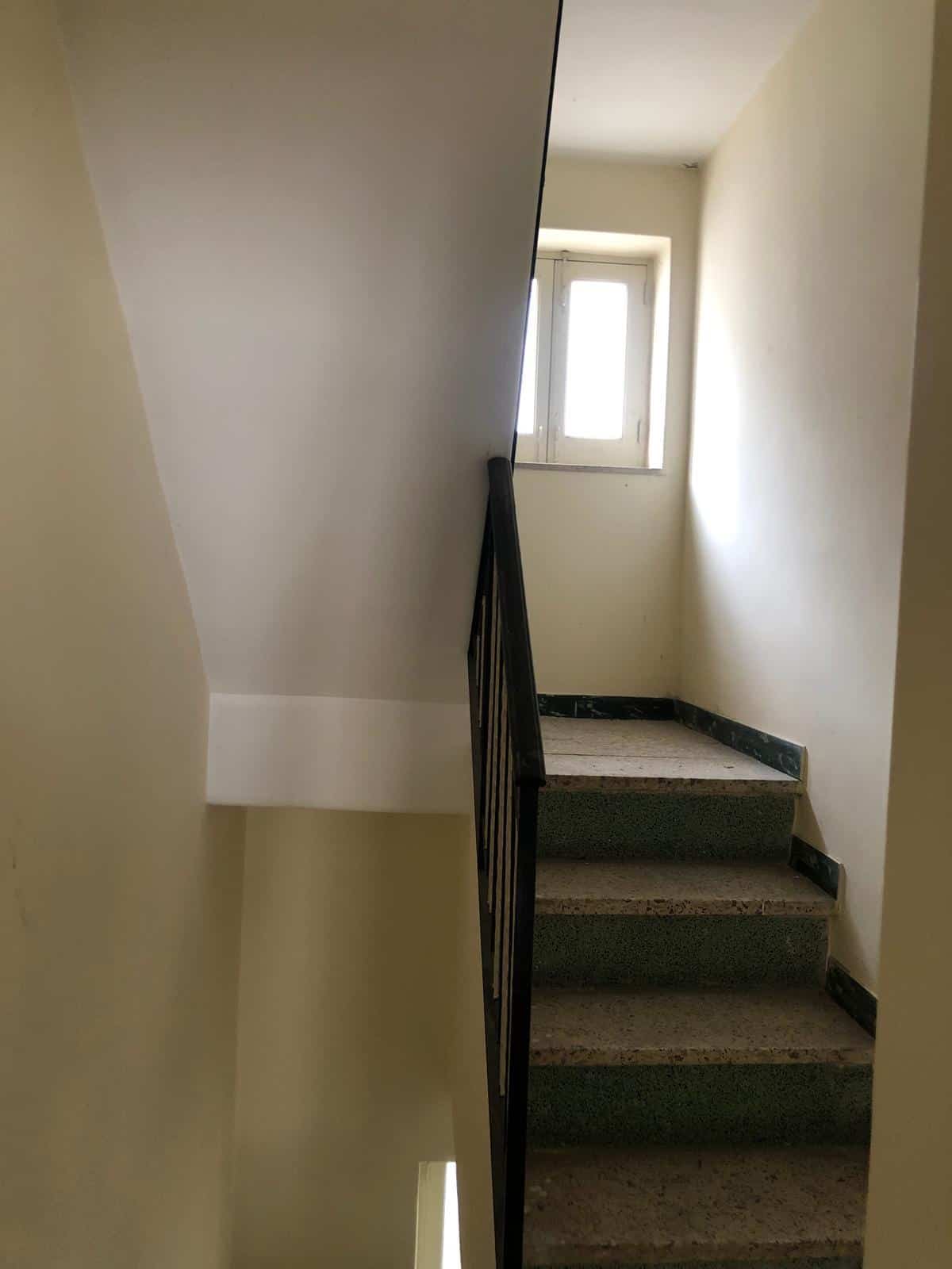 Scala interna in edificio residenziale, pareti chiare, finestra naturale, pavimentazione in marmo, design funzionale, ristrutturazione recente, luminoso e accogliente ambiente abitativo, ideale per appartamenti moderni.