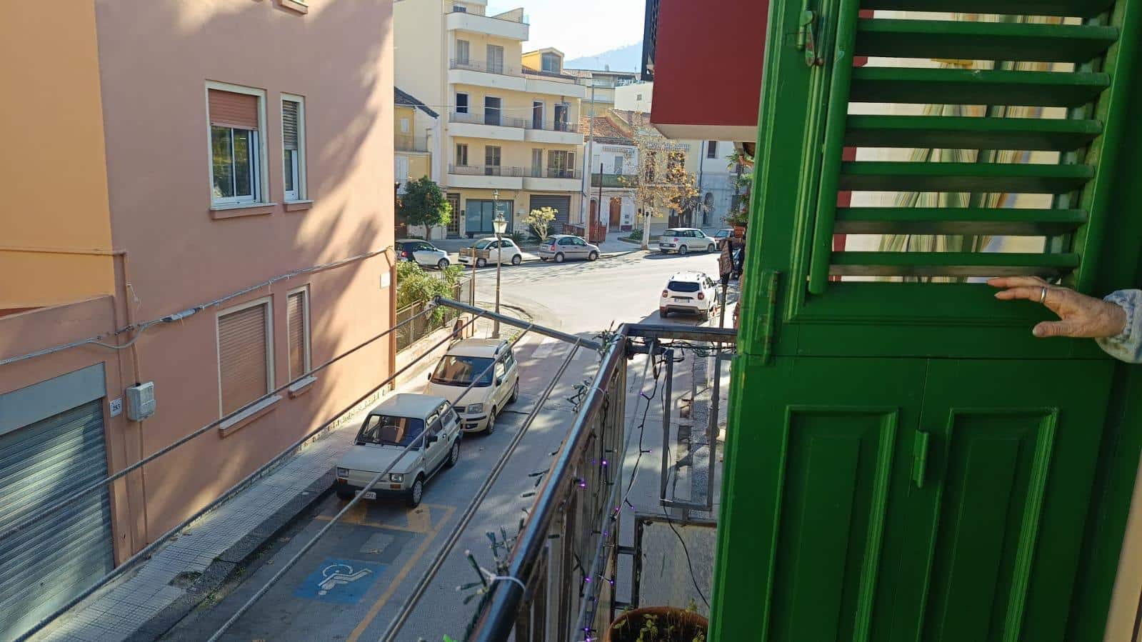 Balcone con vista su strada in quartiere residenziale, con auto parcheggiate e palazzi circostanti, in stile urbano e tranquillo.