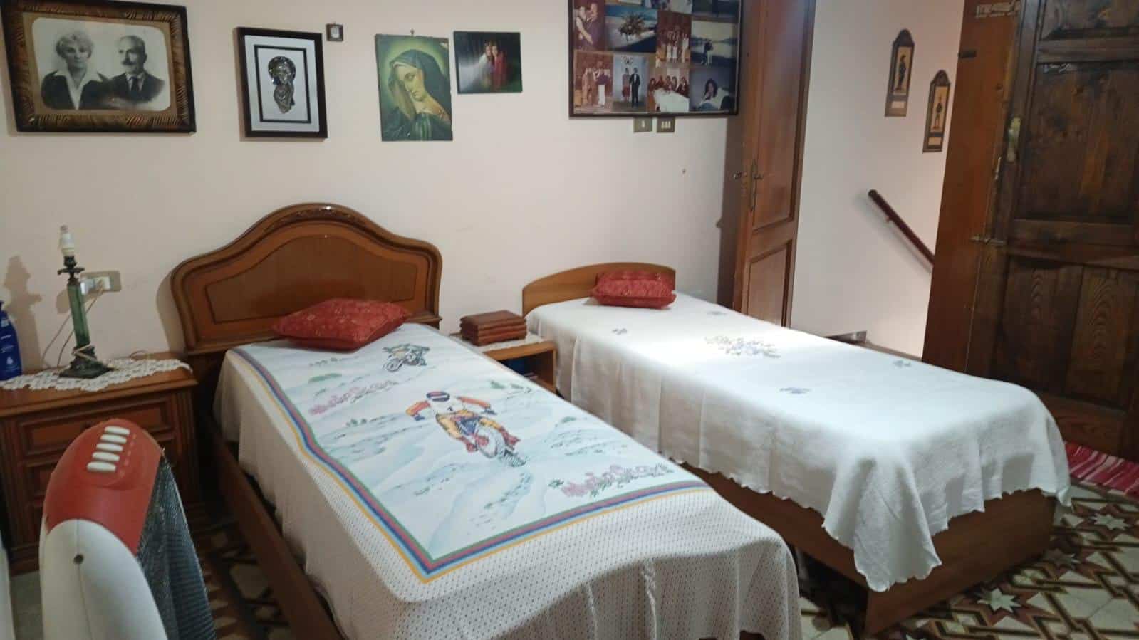 Letto matrimoniale e letto singolo in camera da letto arredata in stile classico con quadri alle pareti e mobili in legno, ambiente accogliente e familiare.