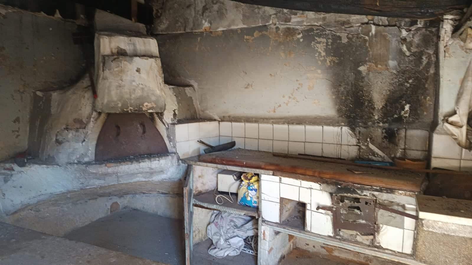 Forno rustico in pietra e mattoni, cucina funzionale in stile tradizionale con un'area di lavoro in legno, pareti in pietra e muratura, ideale per ristrutturazione o rinnovamento.