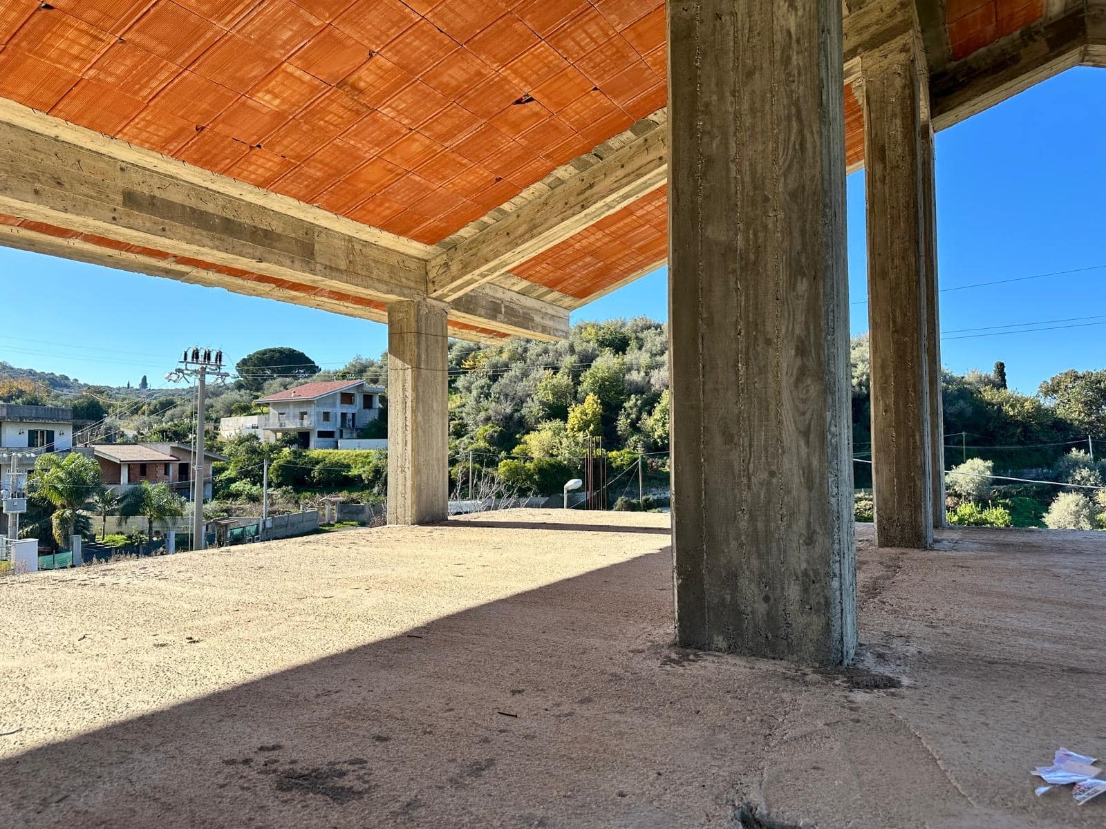 Piantina di un edificio in costruzione con struttura in cemento armato e tetto in matenere, vista panoramica sulla collina e sulle case circostanti, creata da NextCasa per immobili di nuova costruzione.