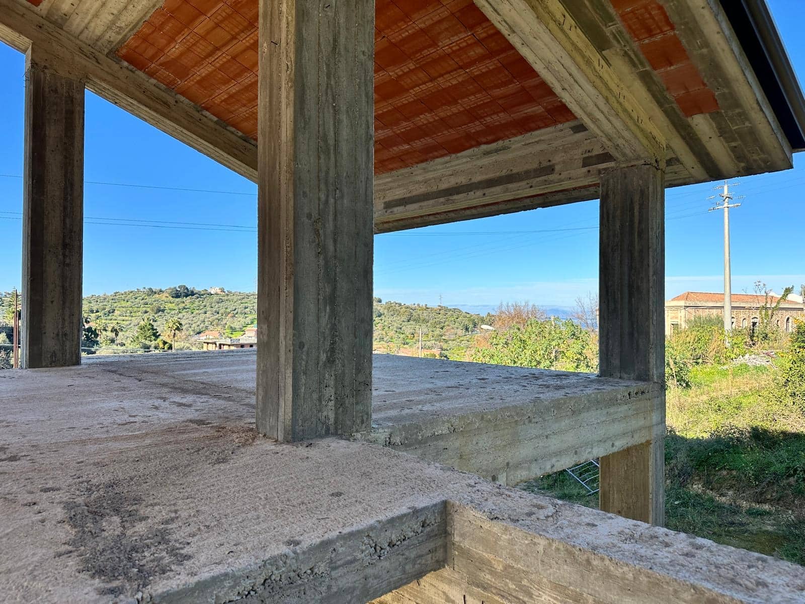 Pilastro in cemento e struttura in costruzione di una casa moderna con vista sul paesaggio naturale circostante.