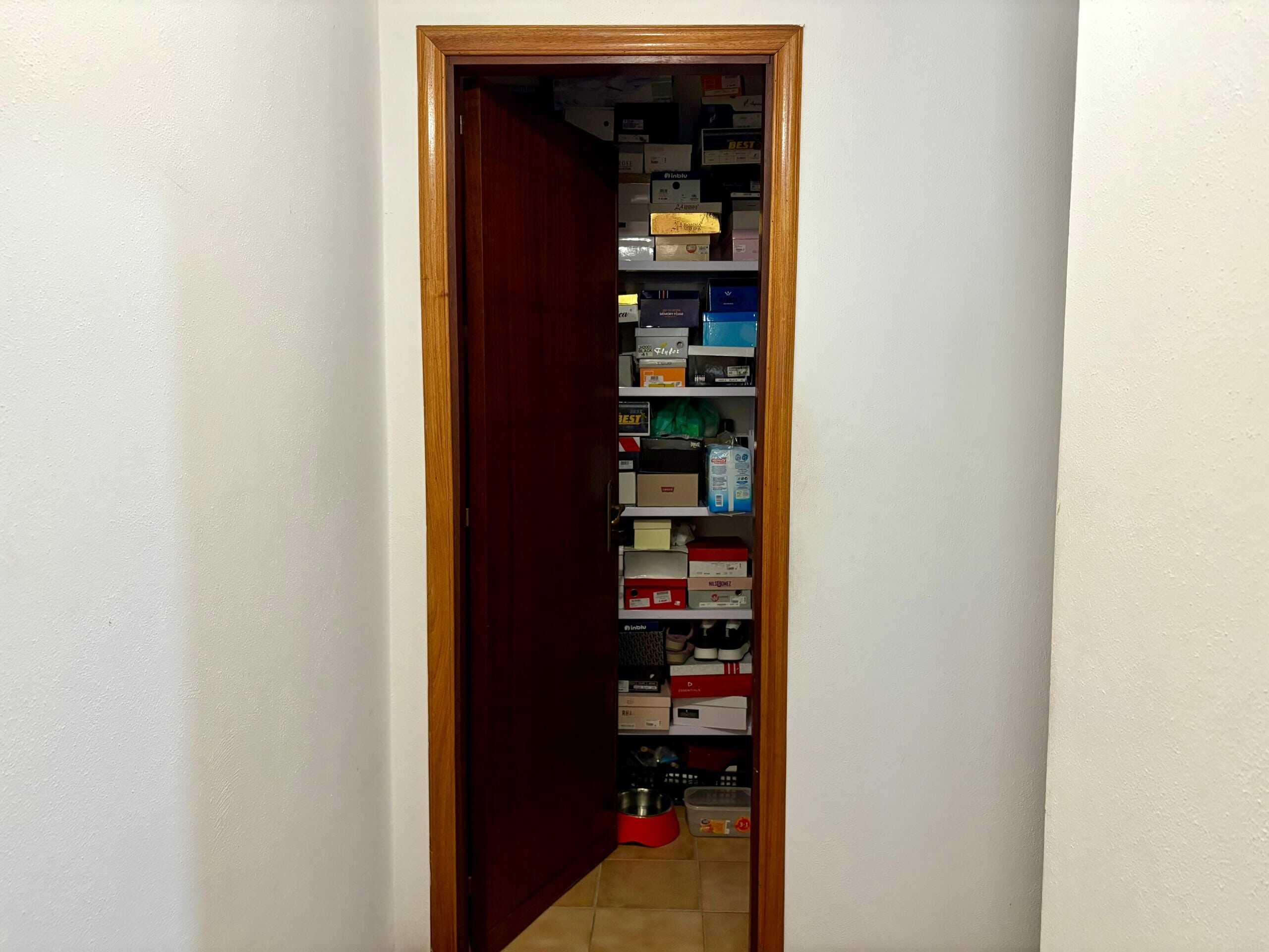Scaffale a ripiano con cibo e scatole di immagazzinaggio in un armadio chiuso, vista interna di una dispensa o soffitta con vari oggetti e scatole per lo stoccaggio.