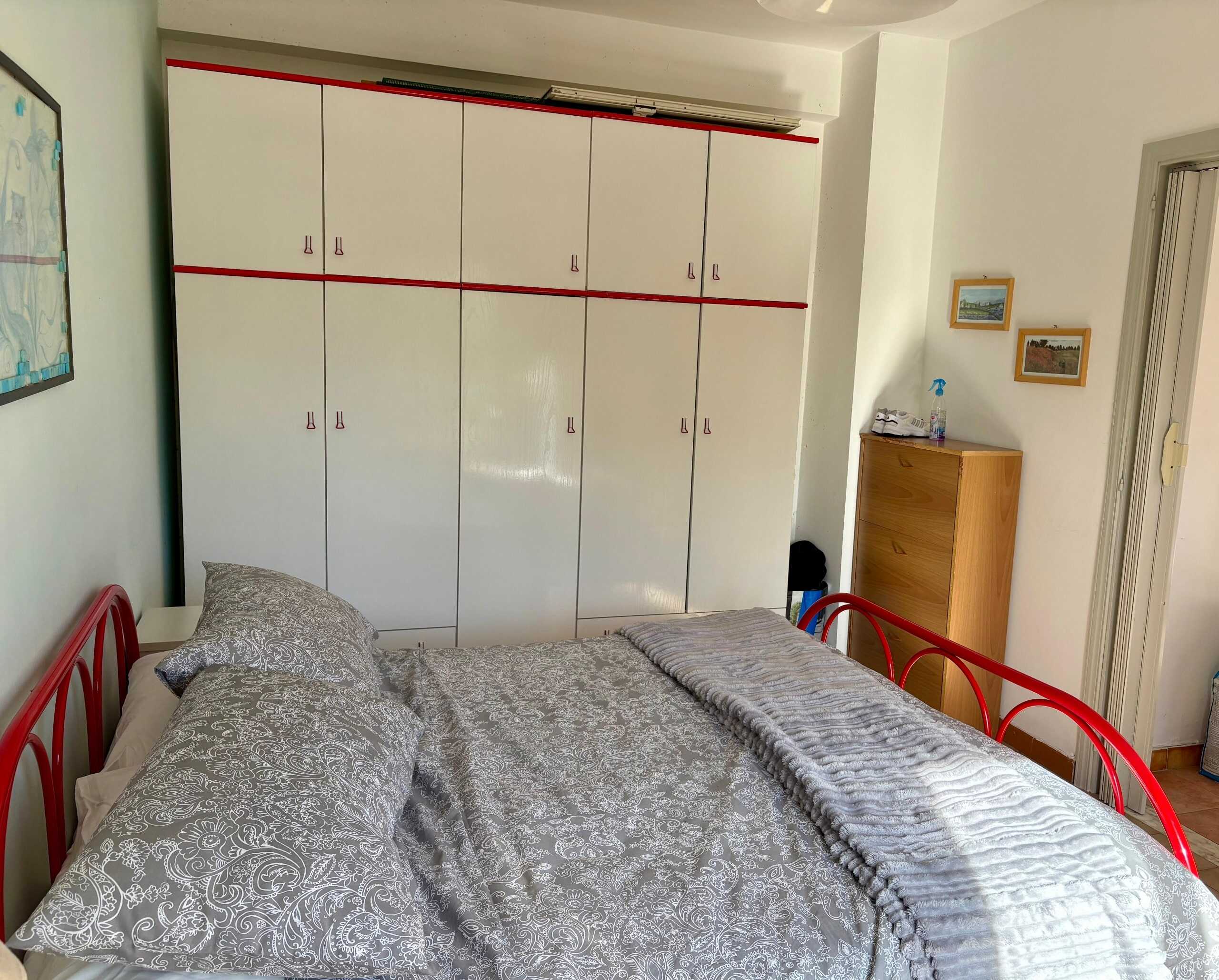 Armadio a muro in camera da letto, letti con biancheria coordinata, arredamento semplice e funzionale, stile moderno, mobili pratici, spazio intelligente per abitazioni, soluzioni di arredo NextCasa.