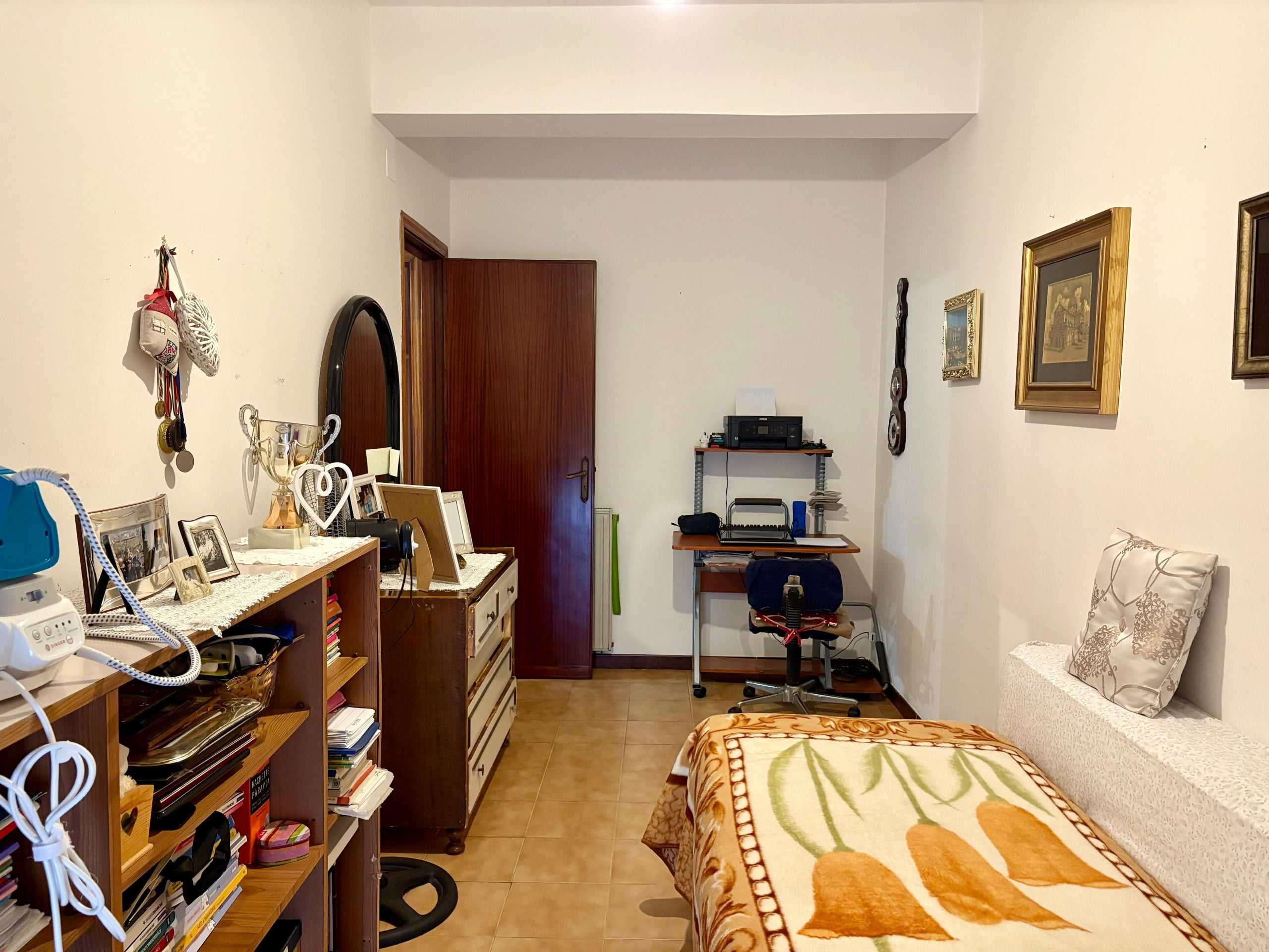 Stanza da letto confortevole con arredi tradizionali, mensole, quadri e accessori, ideale per la vendita di immobili residenziali, con decorazioni accoglienti e spazio per entertainment e studio.