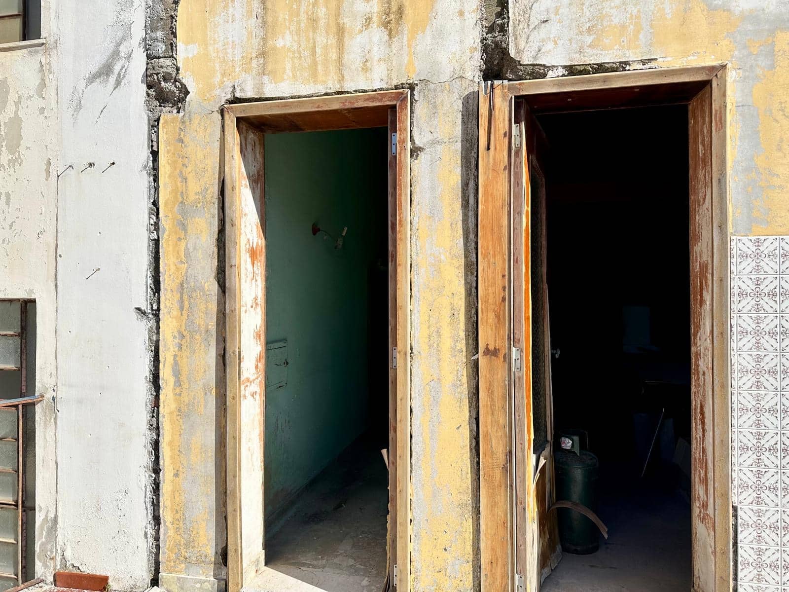 Finestra di pronto intervento in fase di ristrutturazione su un edificio storico, con dettagli di muratura e mattonelle decorative, pronta per essere rinnovata e valorizzata.