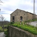 Vecchio casale in pietra rurale con tetto in terracotta, situato in un paesaggio naturale con vista sulle colline, ambiente tranquillo e autentico, ideale per progetti di ristrutturazione o come immobile storico.