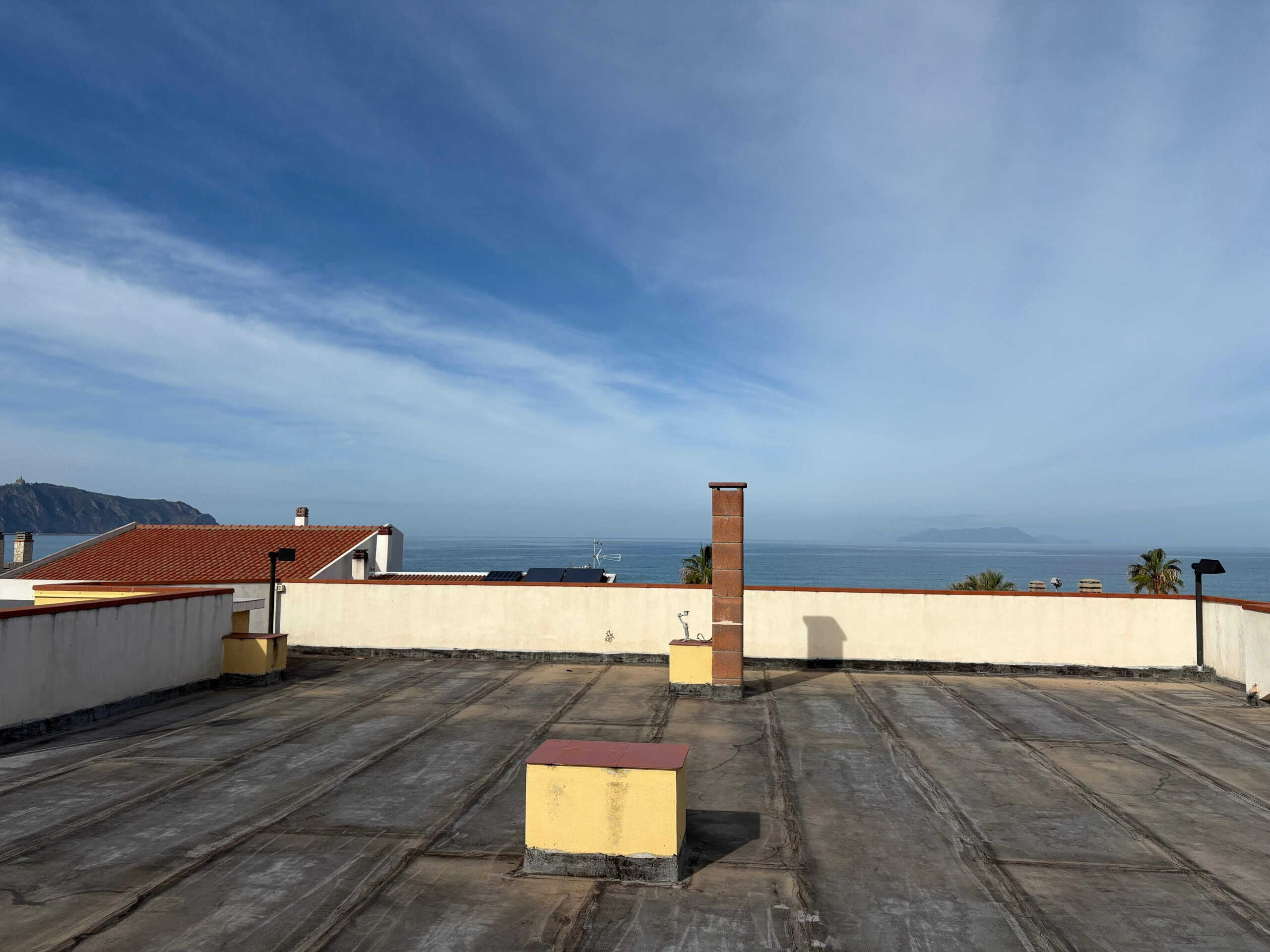 Vasta panoramica sul mare dal tetto di un immobile con vista sull'oceano e sulle case circostanti, ideale per spazi di relax o installazione di pannelli solari.