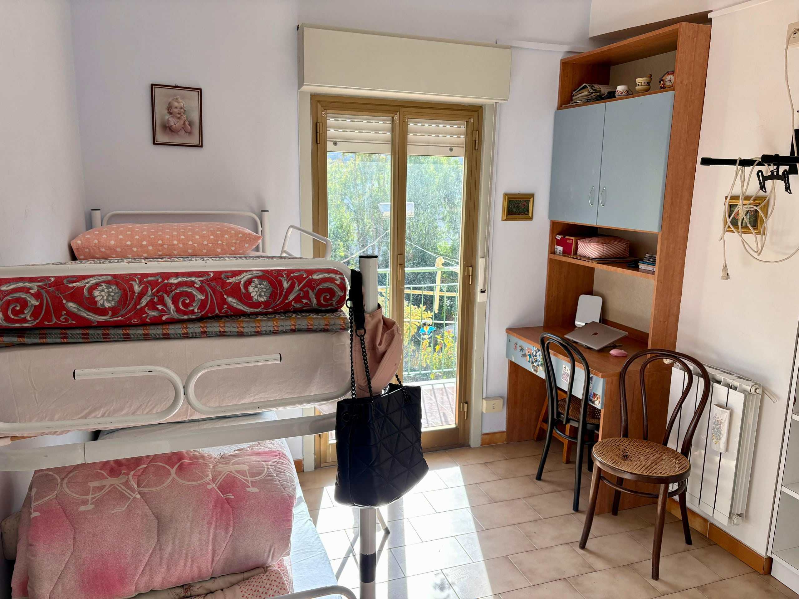 Letto a castello con vista su balcone luminoso, arredo pratico e funzionale in camera singola, ideale per vivere in modo confortevole ogni momento.