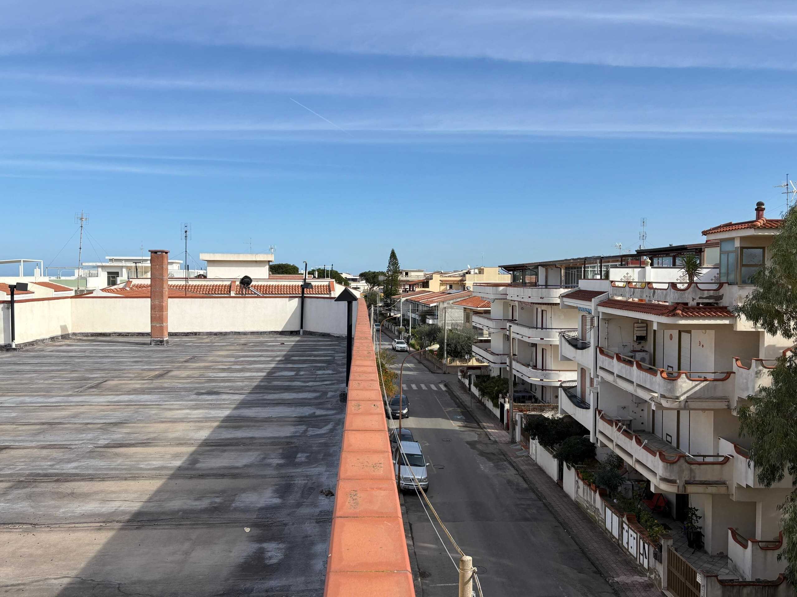Tetto di un edificio residenziale con vista sulle case del quartiere e il cielo azzurro.