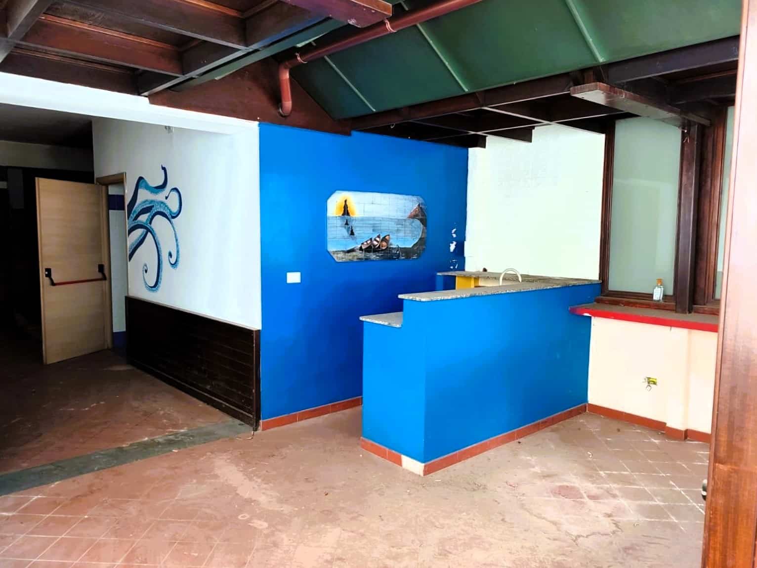 Spiaggia dipinta su parete blu e arancione, angolo cottura con bancone in granito, pareti colorate e decorazioni artigianali, arredamento unico e vivace, ambiente ideale per soggiorni rilassanti e divertenti.