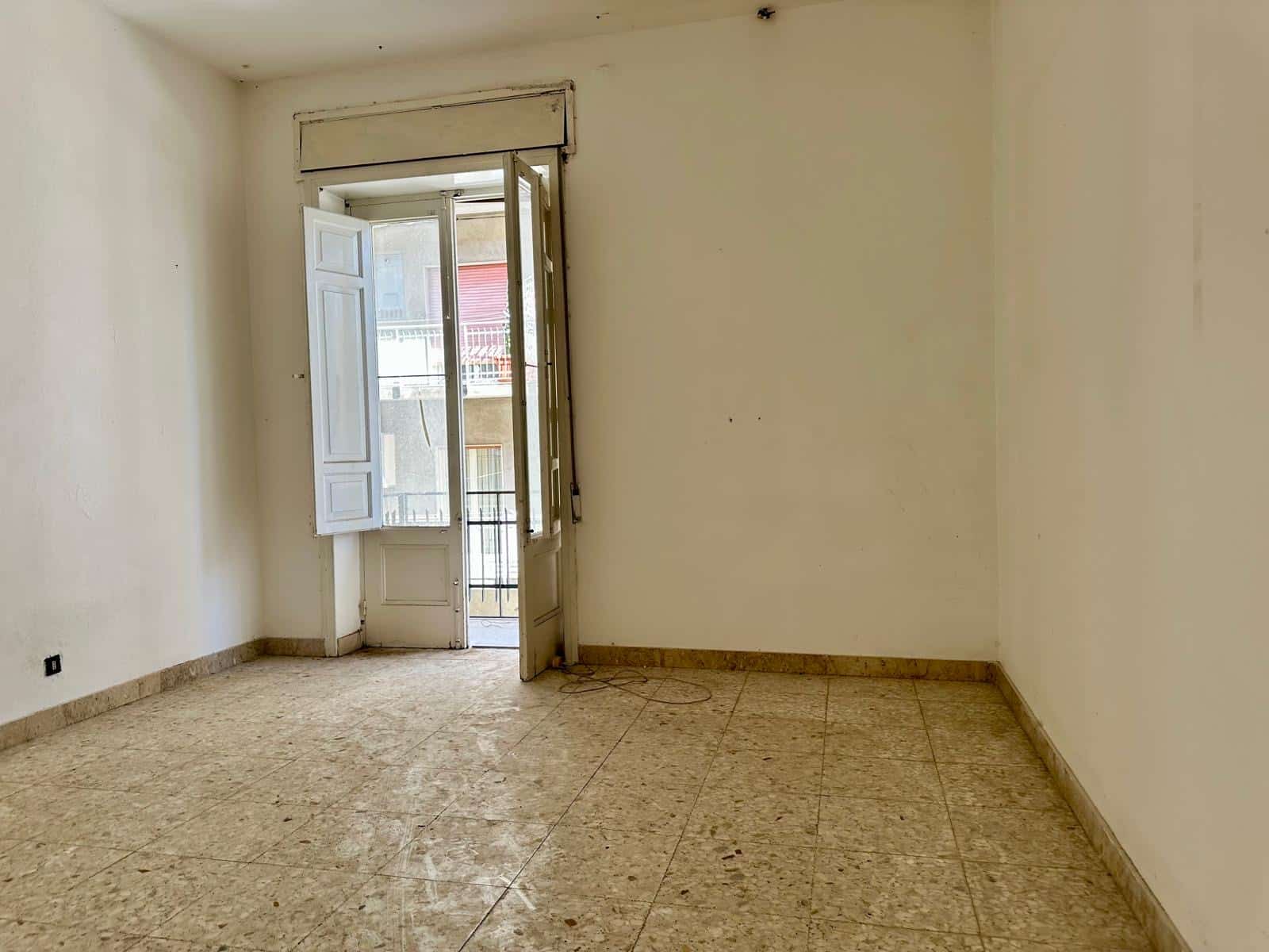 Finestra con persiane e balcone in un bilocale vuoto, immobile residenziale in affitto a Napoli, stile classico, pavimento in marmo, ambiente luminoso e spazioso, ideale per investimento immobiliare.