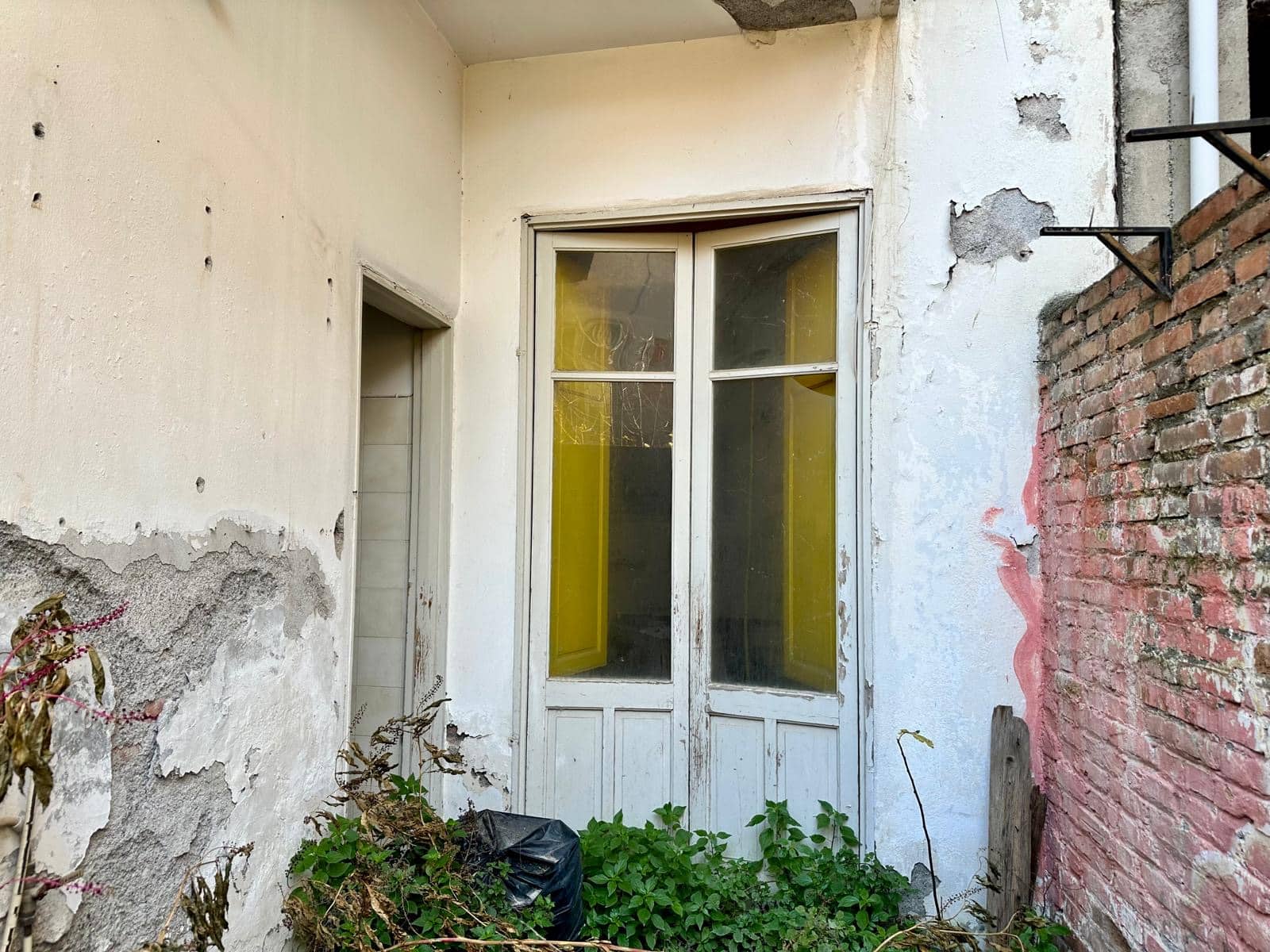 Finestra vecchia in stile rustico con pareti in pietra e mattoni, possibilità di ristrutturazione, in un cortile abbandonato, ideale per progetti di ristrutturazione e valorizzazione di immobili storici a NextCasa.
