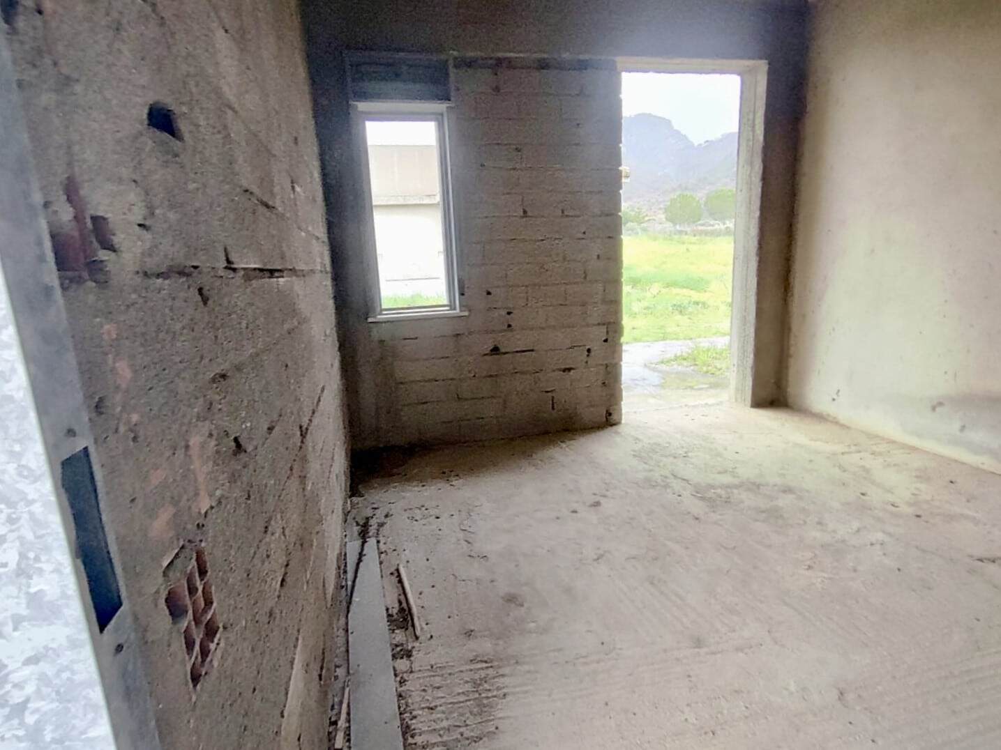 Stanza in costruzione con pareti in pietra e mattoni, luminosa con vista sul paesaggio naturale circostante. Ideale per realizare la casa dei tuoi sogni con materiali di qualità.