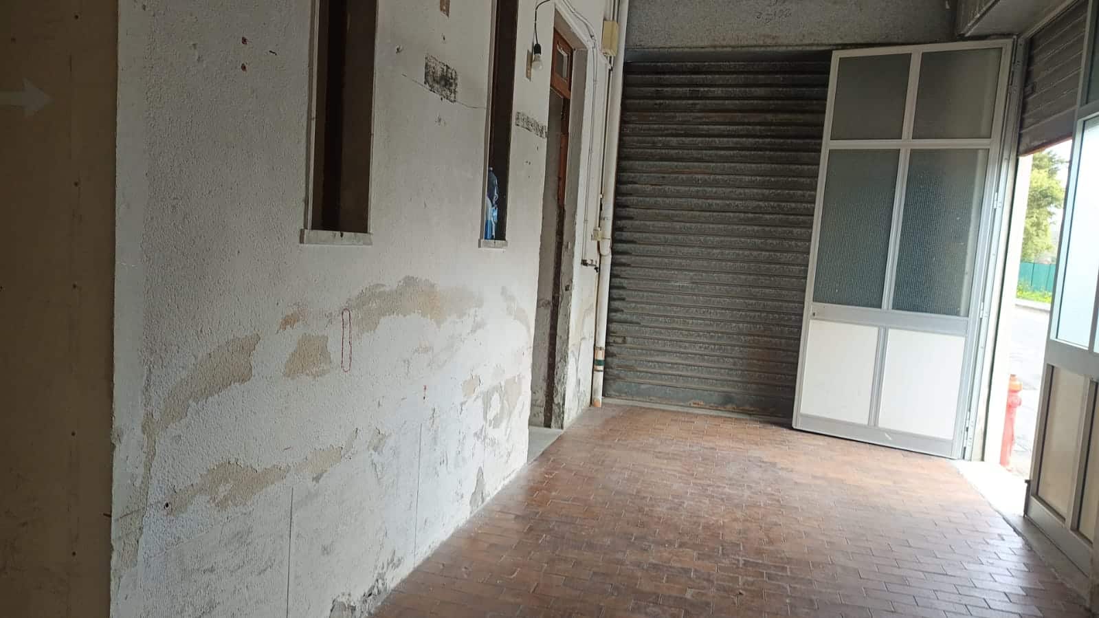 Vano con porta garage e finestre, pronto per ristrutturazione, pavimento in cotto e pareti in fase di lavorazione, ideale per soluzioni residenziali o commerciali.