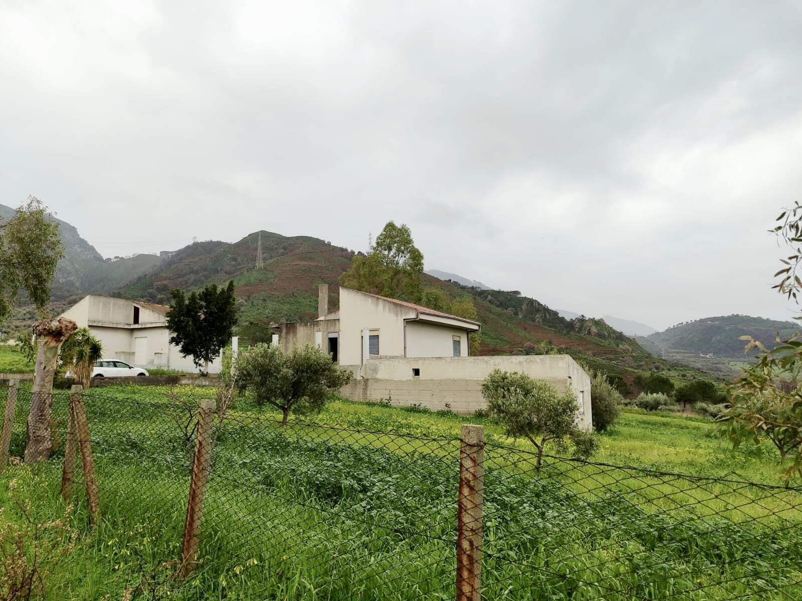 Villa moderna in contesto rurale con vista sulle colline siciliane, progettata da NextCasa, ideale per residenza o investimento in Sicilia, con ampio giardino e architettura contemporanea.