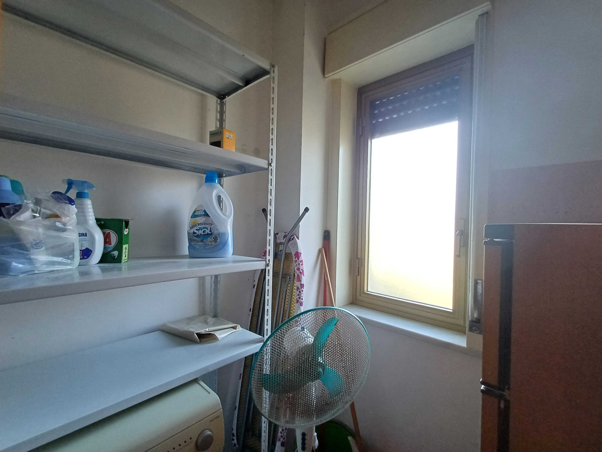 Prodotti per la pulizia e spazio di stoccaggio in lavanderia, con finestra e ambiente ordinato, ideale per soluzioni di organizzazione domestica.