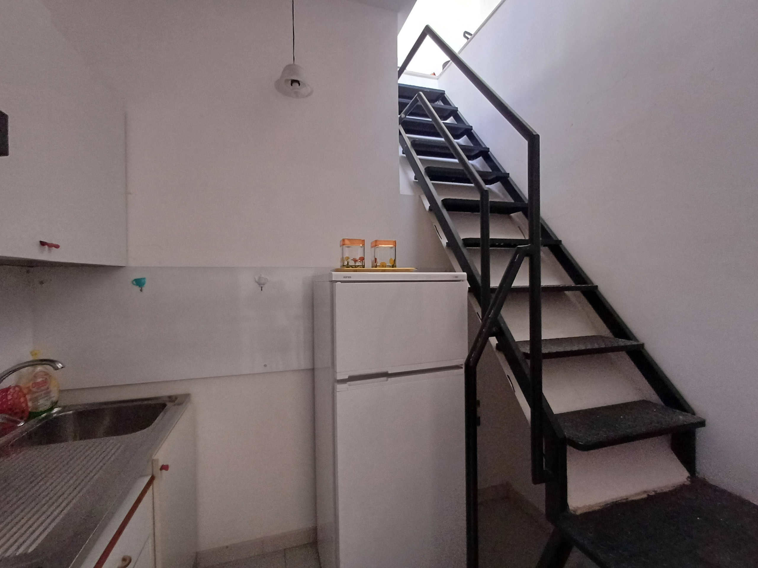 Scala interna moderna di metallo nero in un ambiente abitativo con finestra illuminata, perfetta per accesso ai piani superiori in appartamenti o case.