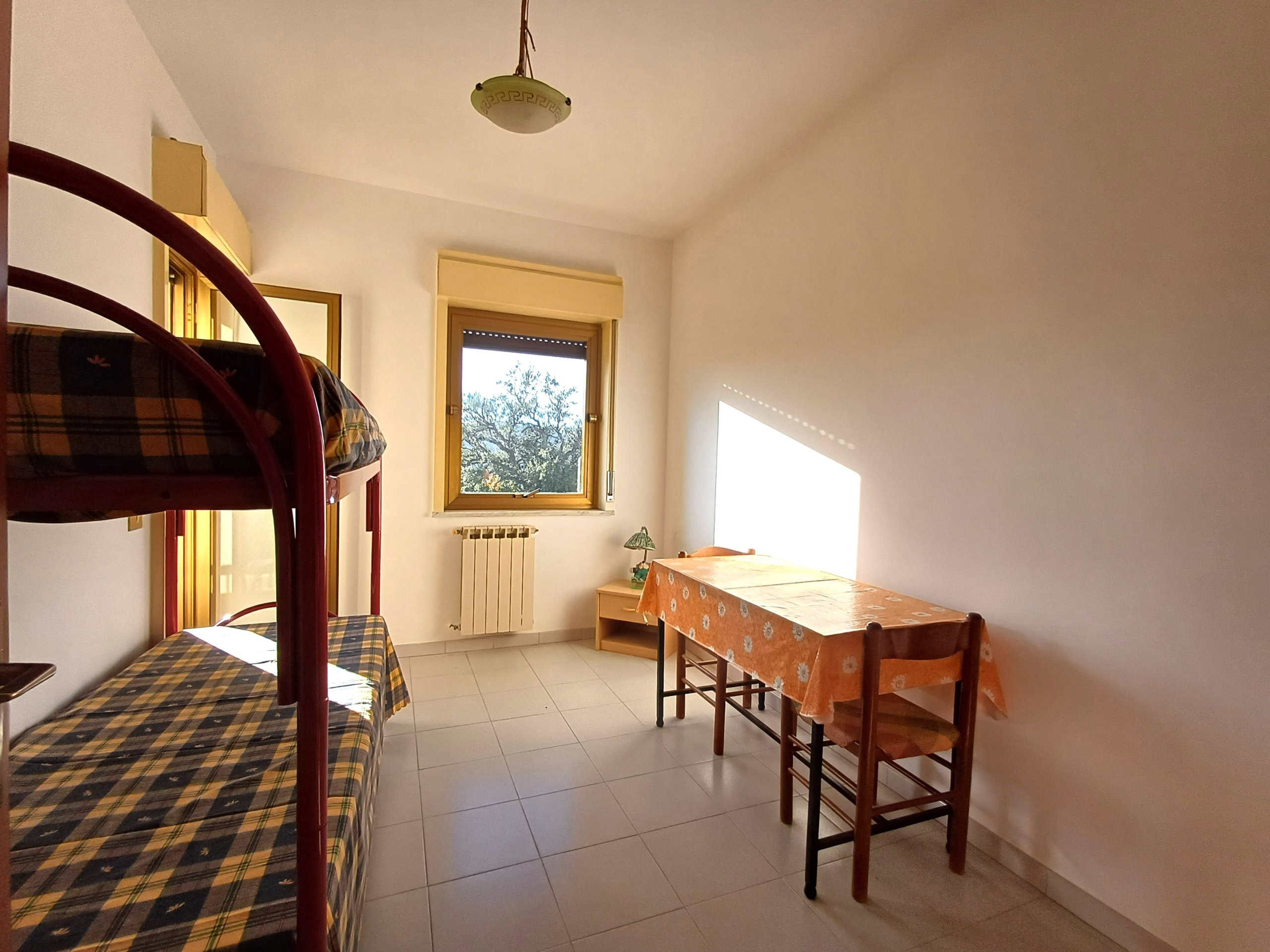 Camera da letto con letti a castello, finestra luminosa e arredi semplici, ideale per affitti brevi o come stanza single in appartamenti in affitto a Roma. Ottima soluzione per spazio e comfort.