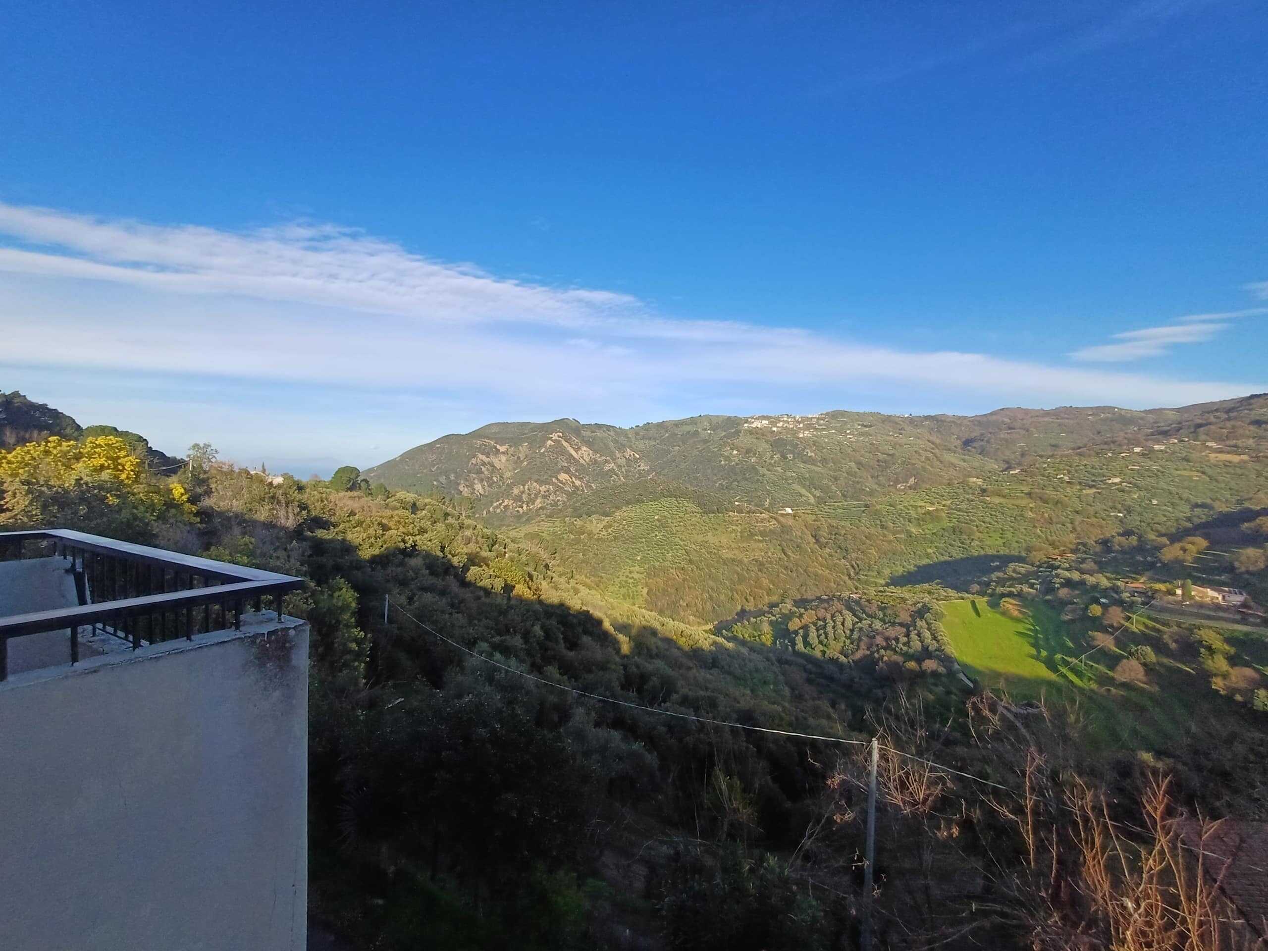 Vista panoramica delle colline e montagne della campagna siciliana, con cielo azzurro e dettagli delle zone verdi e coltivate, ideale per case vacanza o immobili di lusso NextCasa.