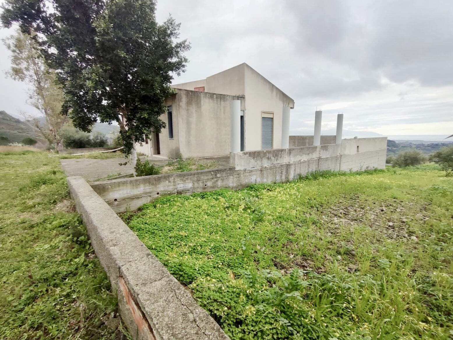 Casa moderna in stile minimal con giardino verde e vista panoramica sulla campagna, ideale per realizzare una residenza isolata e tranquilla immersa nella natura.