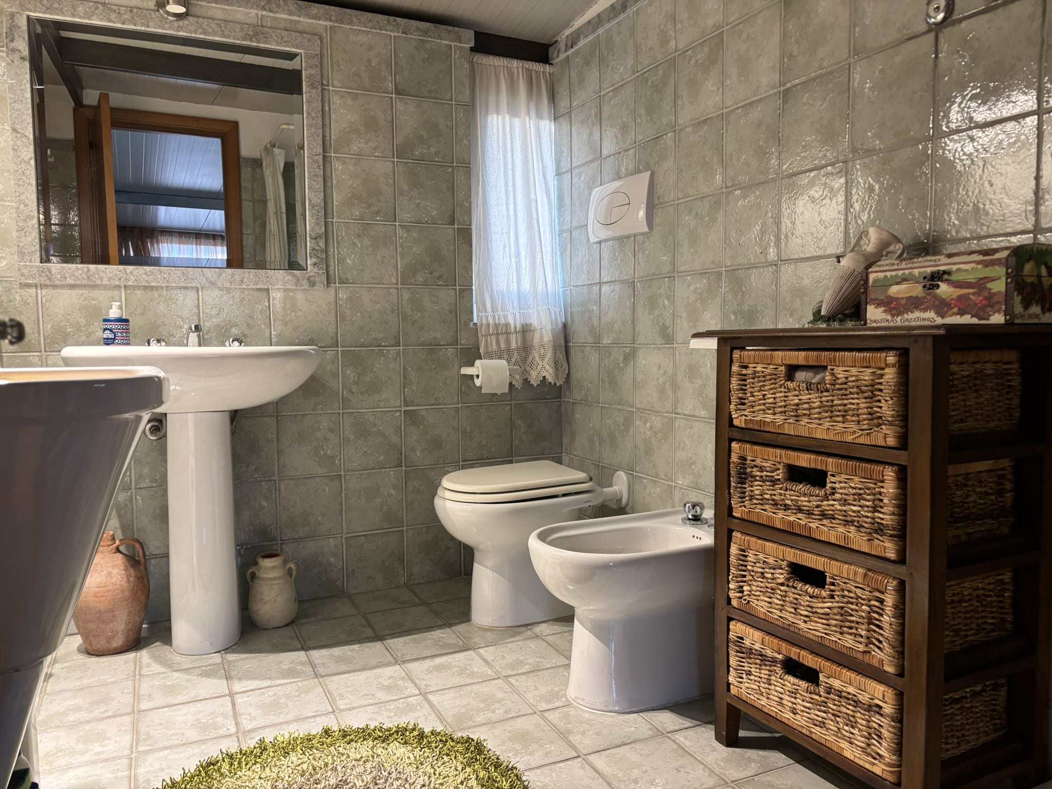 Doccia bagno rustico in stile country, arredi in legno e ceramica verde, bagno funzionale e accogliente, stile tradizionale italiano, NextCasa settore immobiliare.