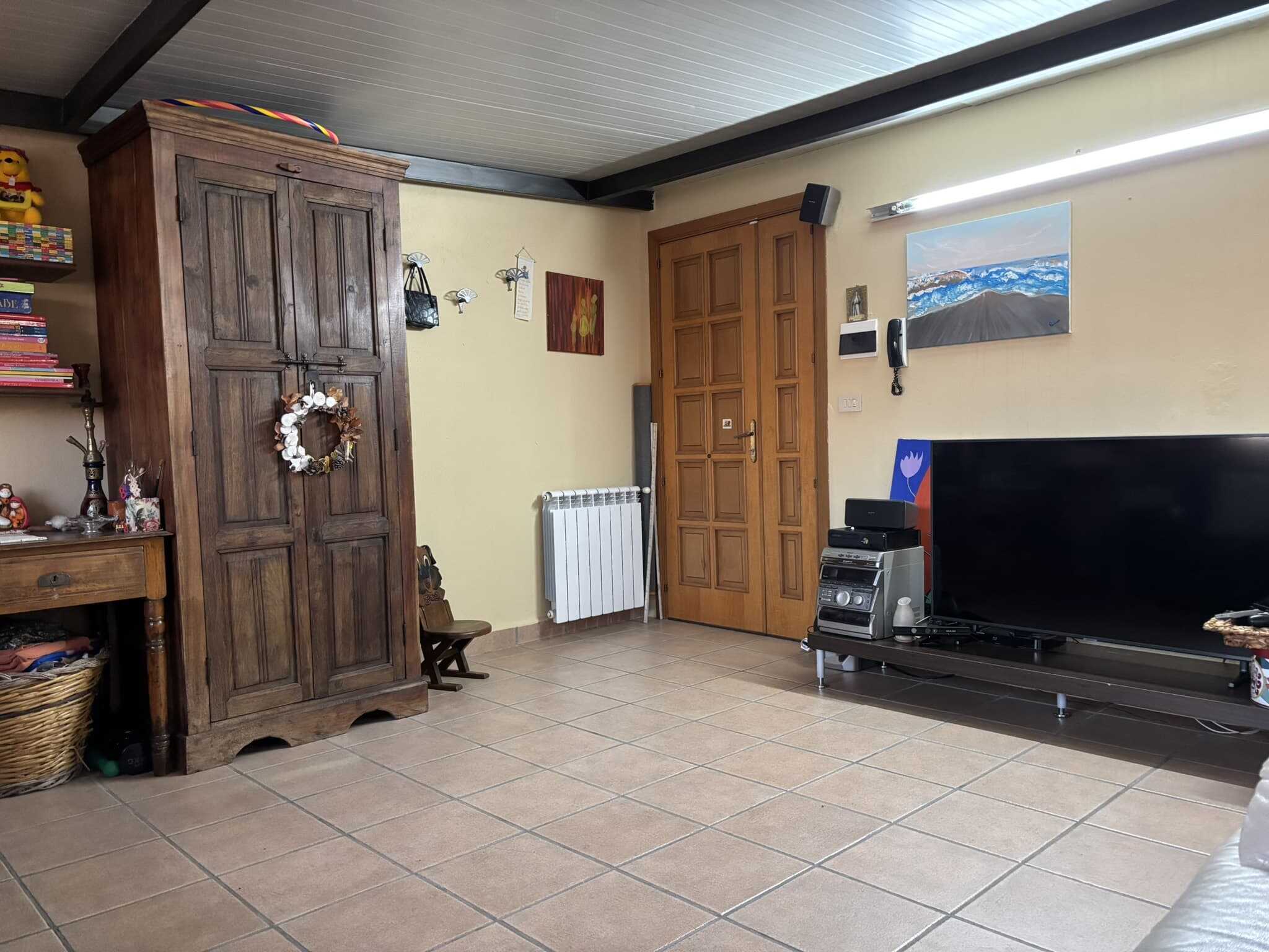Armadio antico in legno nella sala living con televisore, stereo e decorazioni, ambiente accogliente e funzionale.