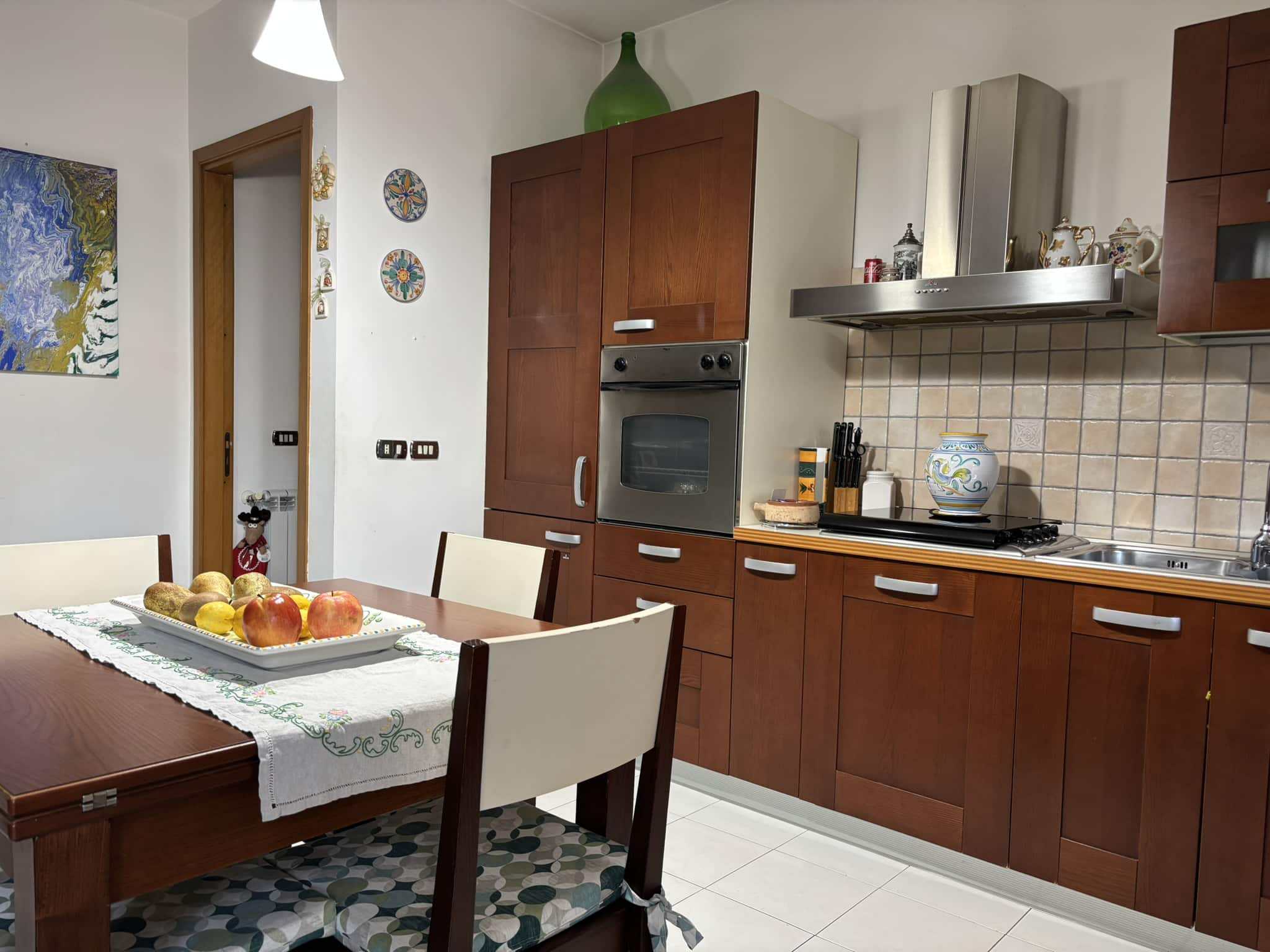 Frigorifero, cucina moderna in legno, piano cottura a gas, stoviglie decorative, arredamento funzionale, spazio cucina elegante, dettagli di decorazione, elettrodomestici in acciaio inox, ambiente di casa accogliente, mobili di qualità, cucina abitabile di design.