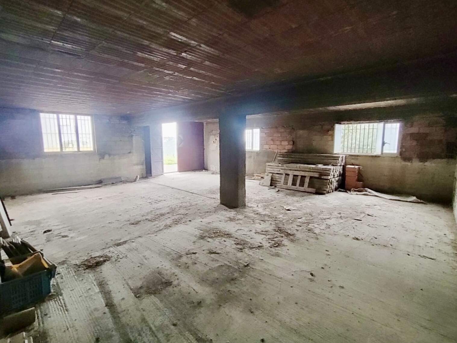Ampio spazio interno di una casa in costruzione con pareti in mattoni e soffitto in legno, pronto per la personalizzazione e ristrutturazione, ideale per progetti immobiliari e investimenti.