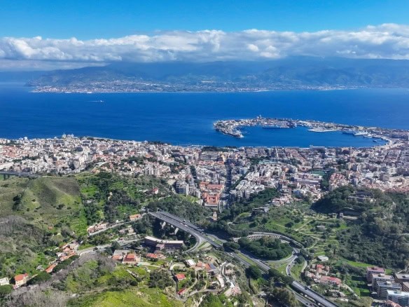 Ville vista mare di Napoli con il Golfo e il Castel dell'Ovo in primo piano, paesaggio urbano, colline verdi e traffico stradale, scenario mozzafiato, attrazioni turistiche, proprietà immobiliari, NextCasa.
