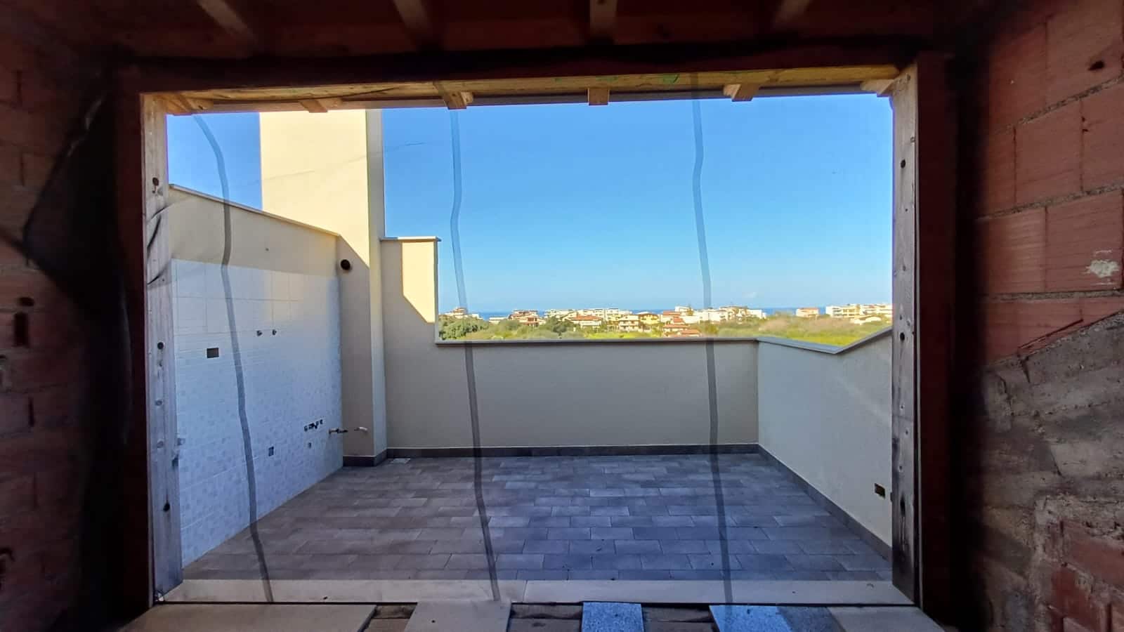 Ampio terrazzo vista mare in costruzione, con pavimentazione in gres e ringhiera in cemento, spazio ideale per relax e panorami mozzafiato.