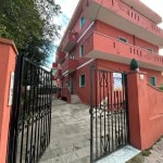 Porte di ingresso di un appartamento in vendita presso NextCasa, edificio residenziale con ampio cortile e vetrate, in zona urbana, con vetrate e cancellate nere, facciata color terracotta, segnale "Vende" affisso.