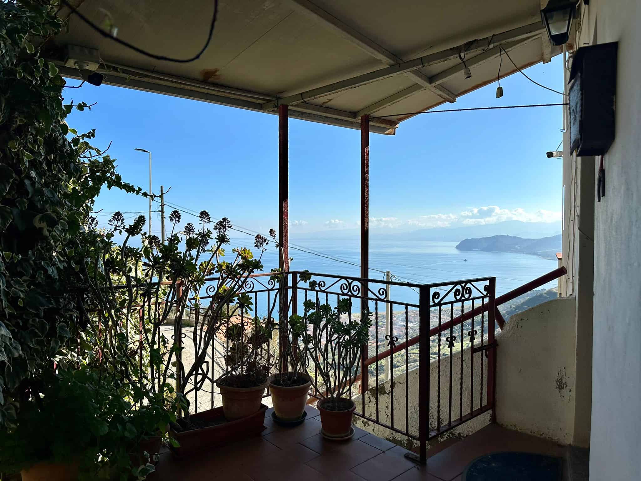 Affaccio su balcone con vista mare, piante in vaso, ambientazione soleggiata, casa nelle Cinque Terre, atmosfera mediterranea, proprietà in vendita, panorama coastal, atmosfera rilassante, immobili vicino al mare, NextCasa.