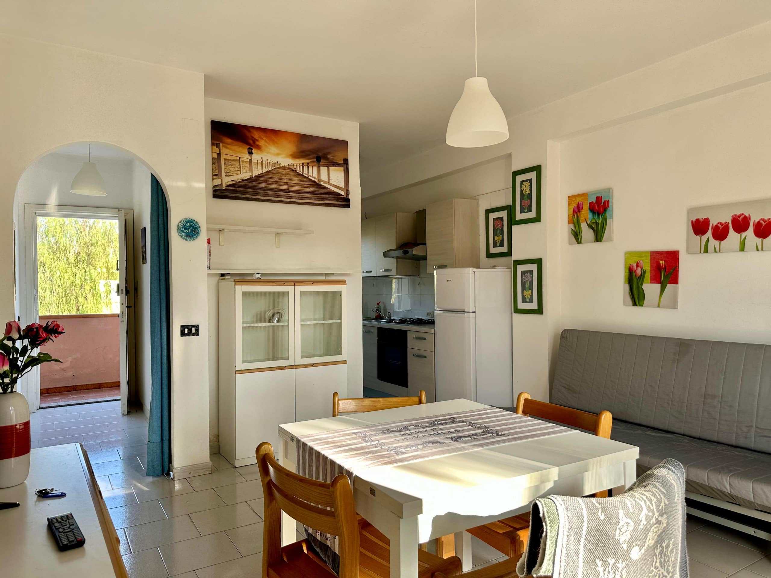 Spazi abitativi luminosi e accoglienti in un appartamento NextCasa, con pareti bianche, decorazioni floreali e arredi funzionali per un soggiorno confortevole e ben arredato.