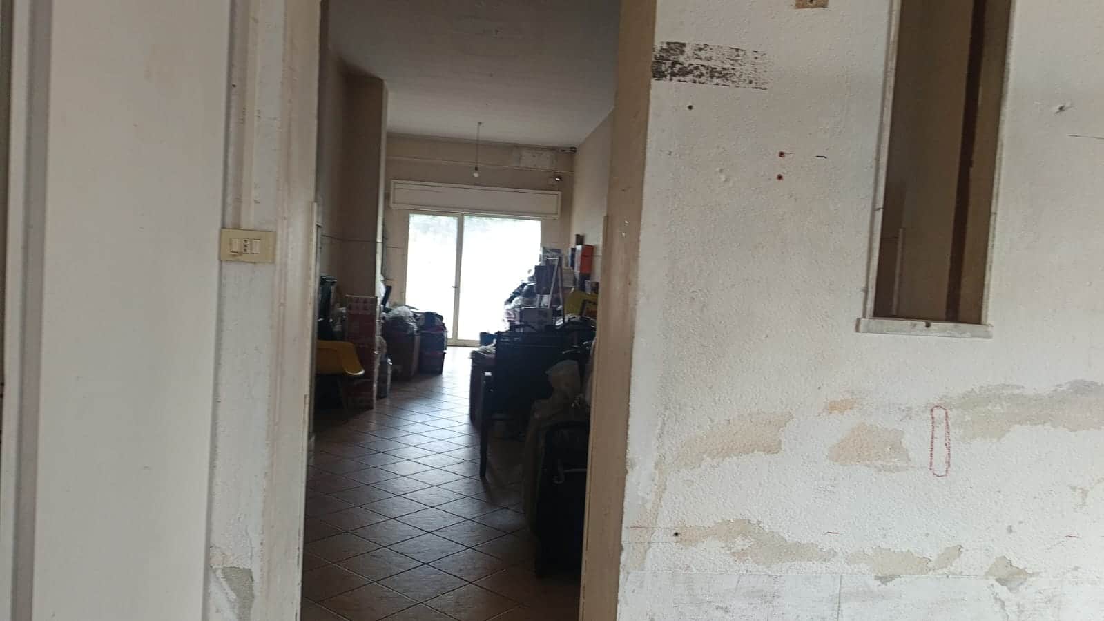 Stanza di casa in fase di ristrutturazione, pareti da verniciare, spazi di soggiorno con oggetti vari e mobili da sistemare in un appartamento in vendita o affitto a NextCasa.