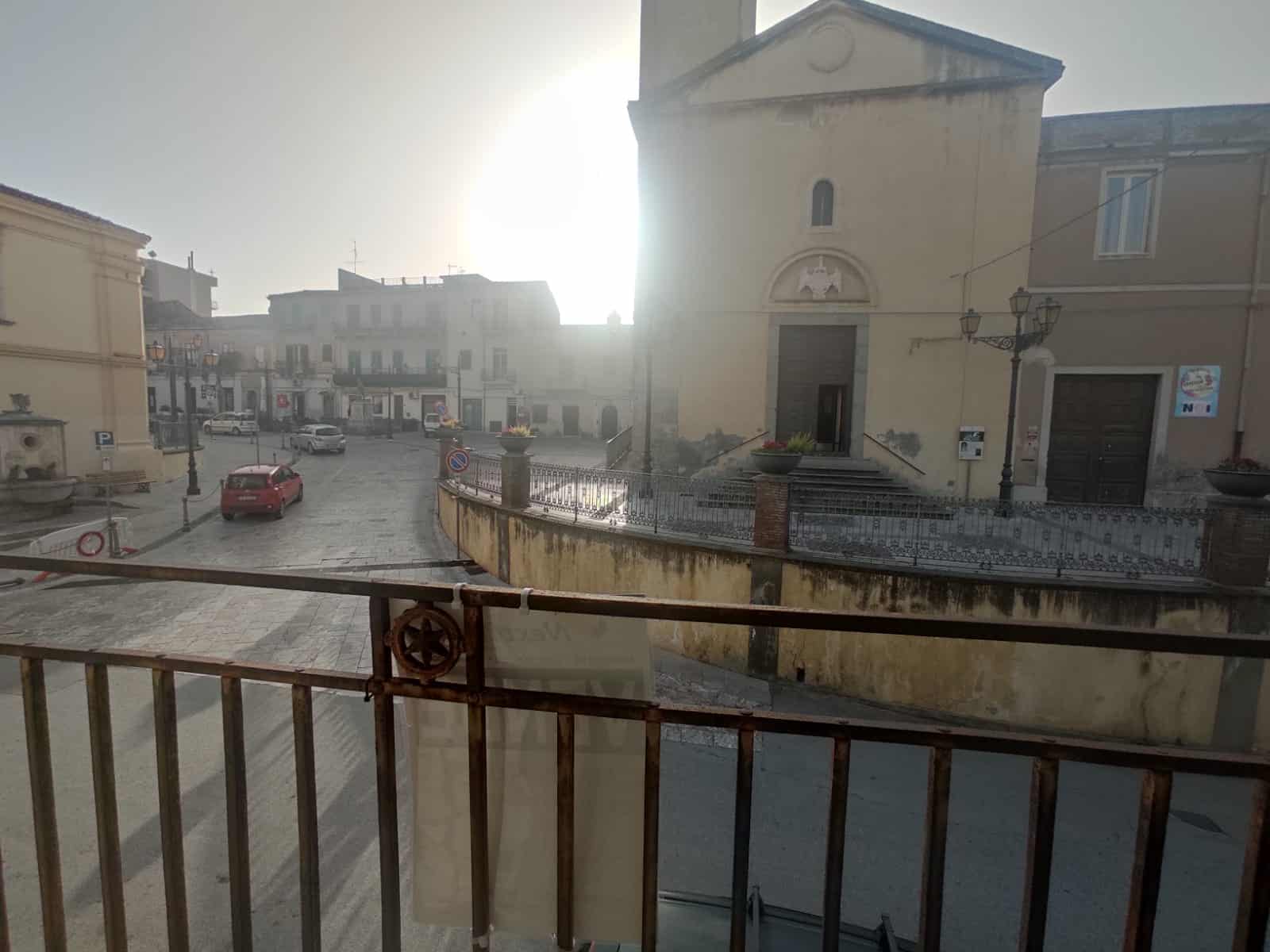 Vicolo storico con edificio religioso e piazza, vista dall'alto con staccionata in ferro, in una città italiana.
