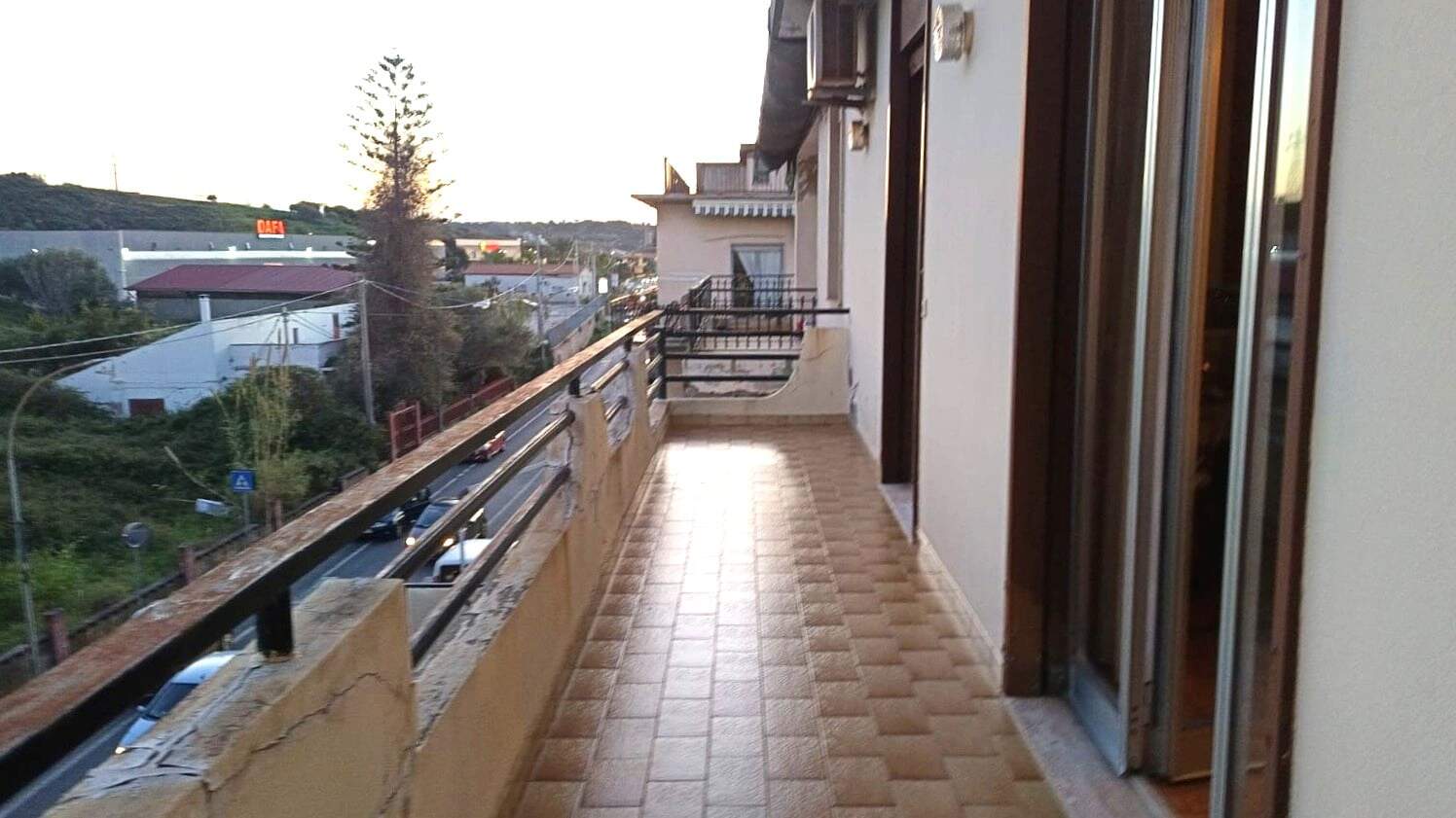 Balcone di un appartamento con vista sulla strada e sulla natura, pavimentato in gres porcellanato, in zona tranquilla e residenziale.