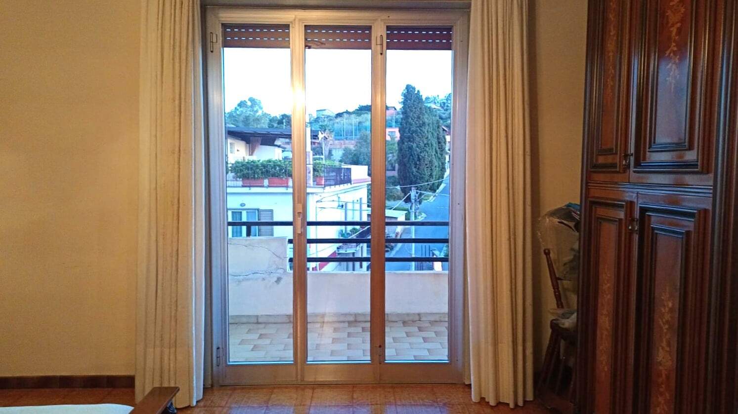 Ampio balcone con porta scorrevole in vetro, vista sulla città e sulla natura, ideale per appartamenti in vendita o affitto, luminosa e ben esposta.