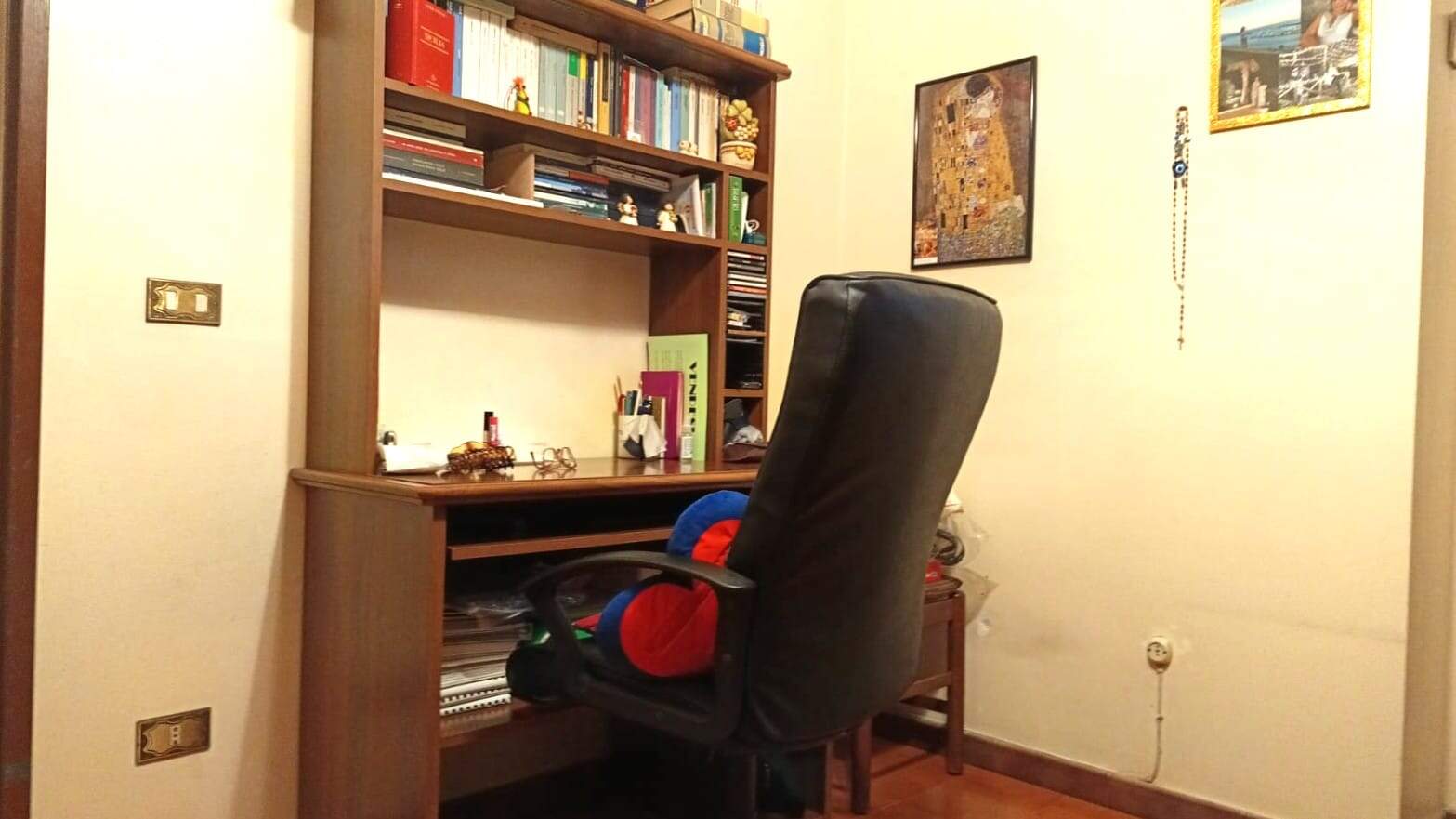 Scrivania in legno con scaffale pieno di libri e oggetti, ambiente di studio o ufficio in casa NextCasa.