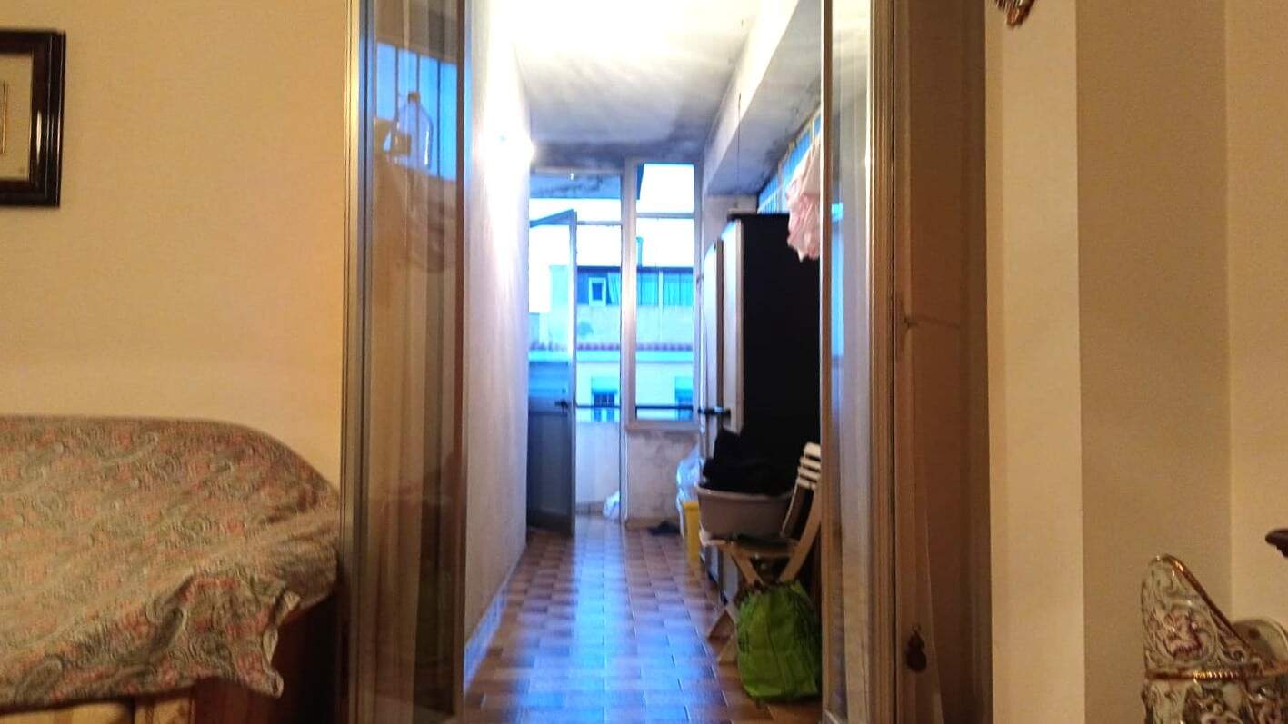 Balcone di un appartamento in centro città, spazio parte di una casa abitabile con soggiorno e accesso a balcone, elementi di arredo e dettagli casalinghi visibili.