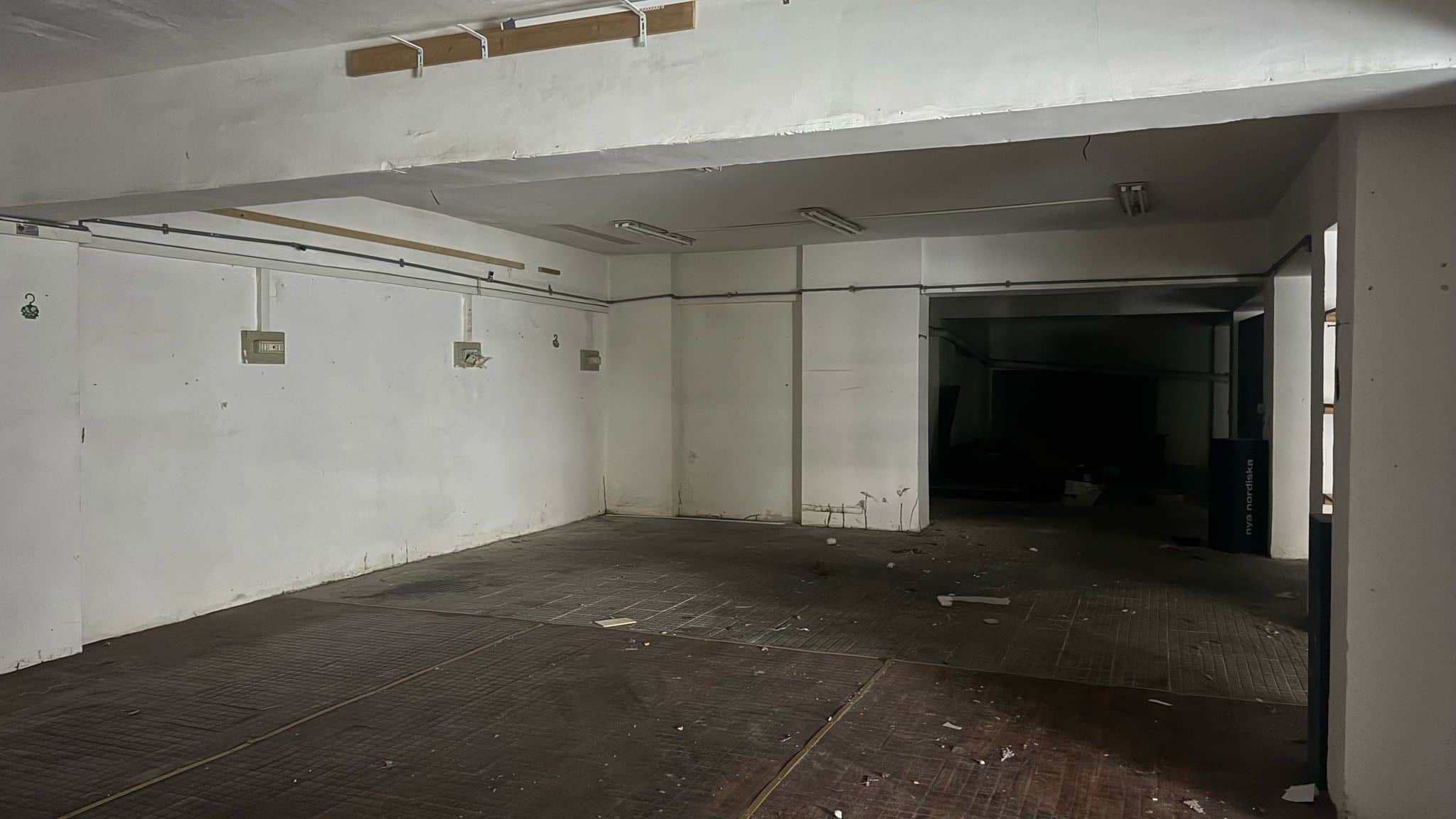 Magazzino vuoto in fase di ristrutturazione, pavimento in legno e pareti bianche con attacchi per dispositivi elettrici, spazio spazioso e luminoso, ideale per investimento immobiliare NextCasa.
