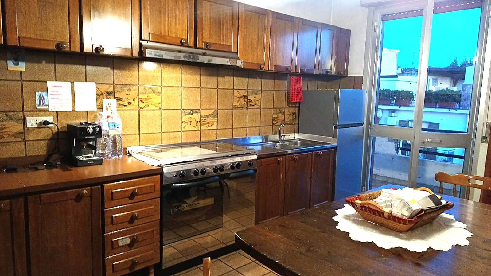 Ottima cucina con mobili in legno, piano cottura a gas, forno, lavello e frigorifero. Spazio ben organizzato con tavolo e arredamento caldo, ideale per la vita quotidiana e pranzi conviviali.