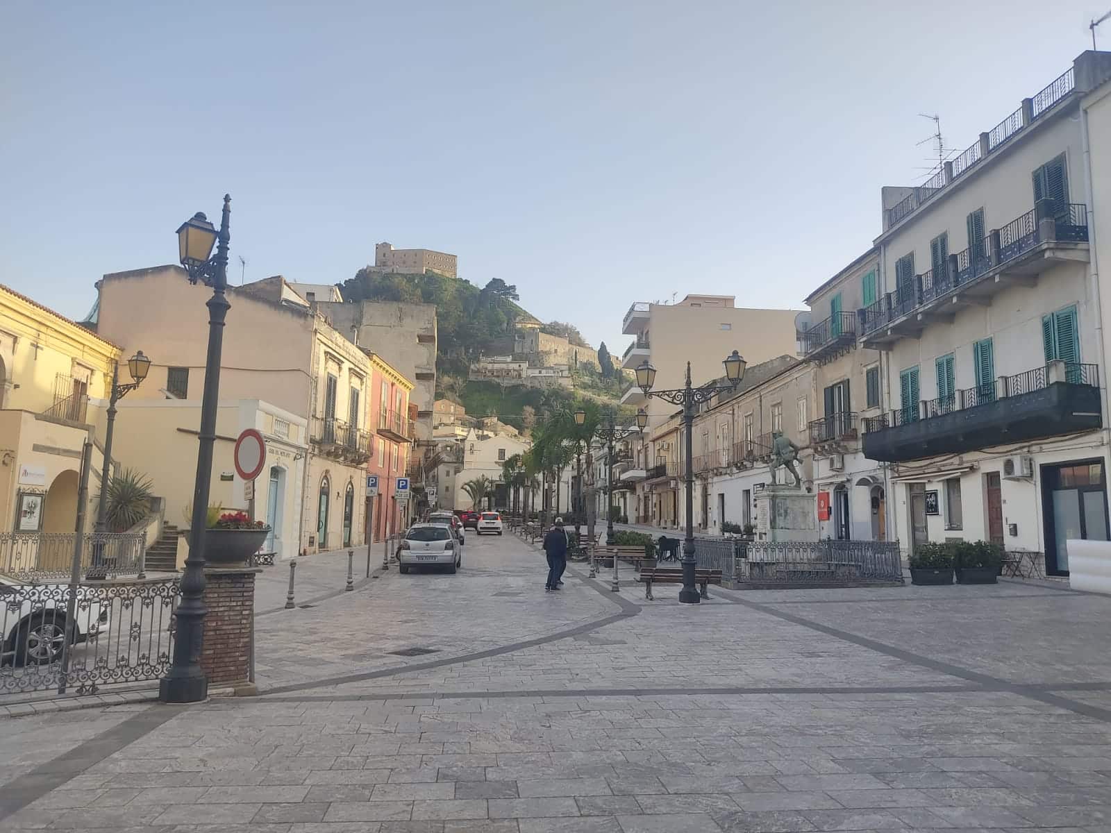Luminoso centro storico di un paese italiano con case colorate, strade lastricate e un castello sullo sfondo. Atmosfera cittadina tranquilla e pittoresca ideale per immobili e investimenti immobiliari.
