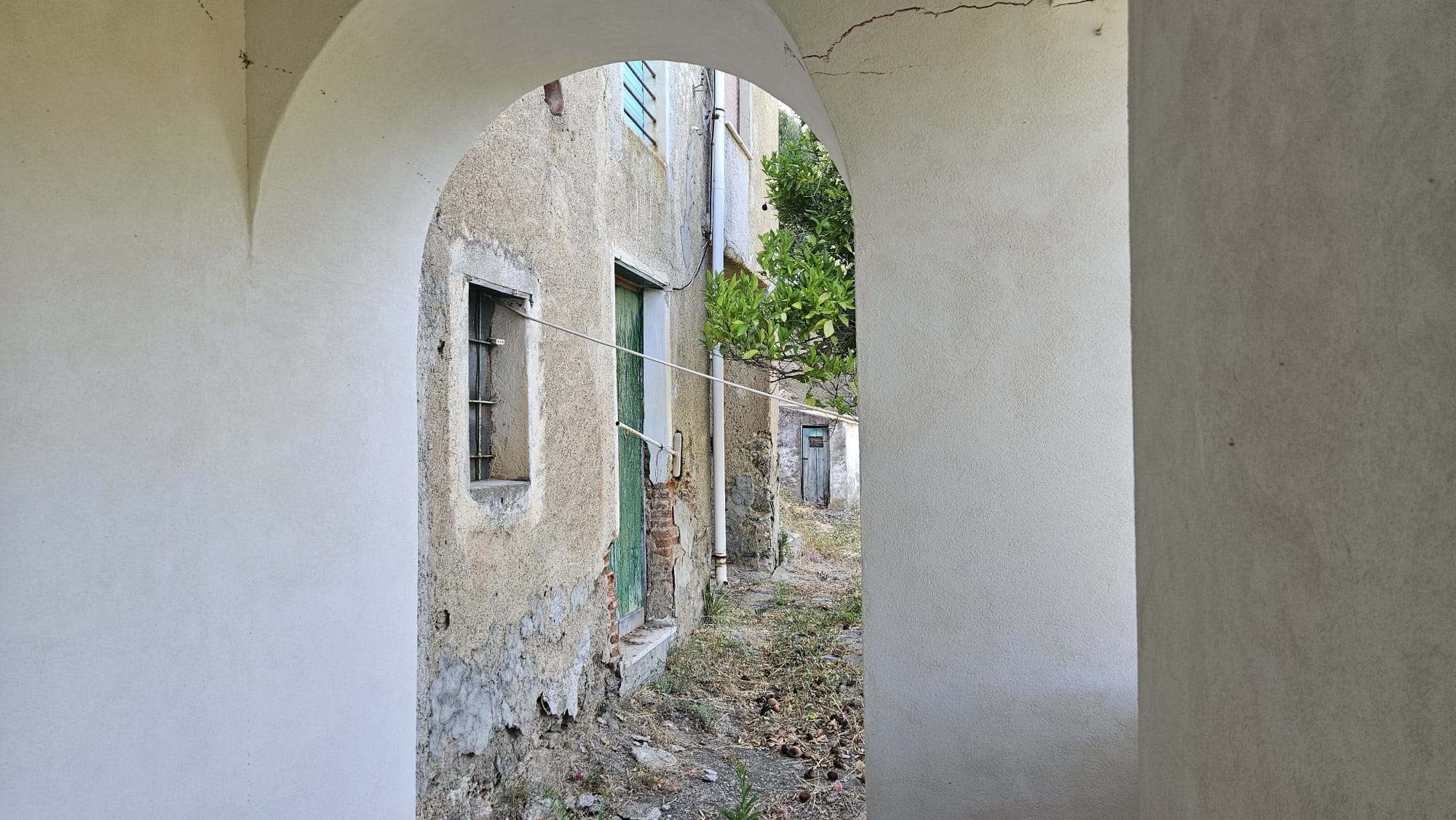 Vecchio muro con finestra e porta, vista su cortile interno di un edificio storico, dettagli di ristrutturazione e pietre a vista, atmosfera autentica e rustica.