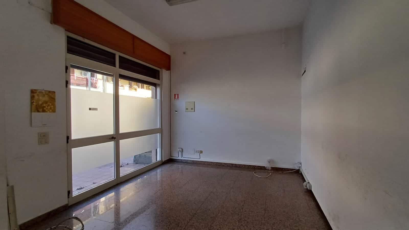 Finestra grande con porta scorrevole in un appartamento vuoto, pareti bianche e pavimento in marmo, pronto per ristrutturazione e personalizzazione.
