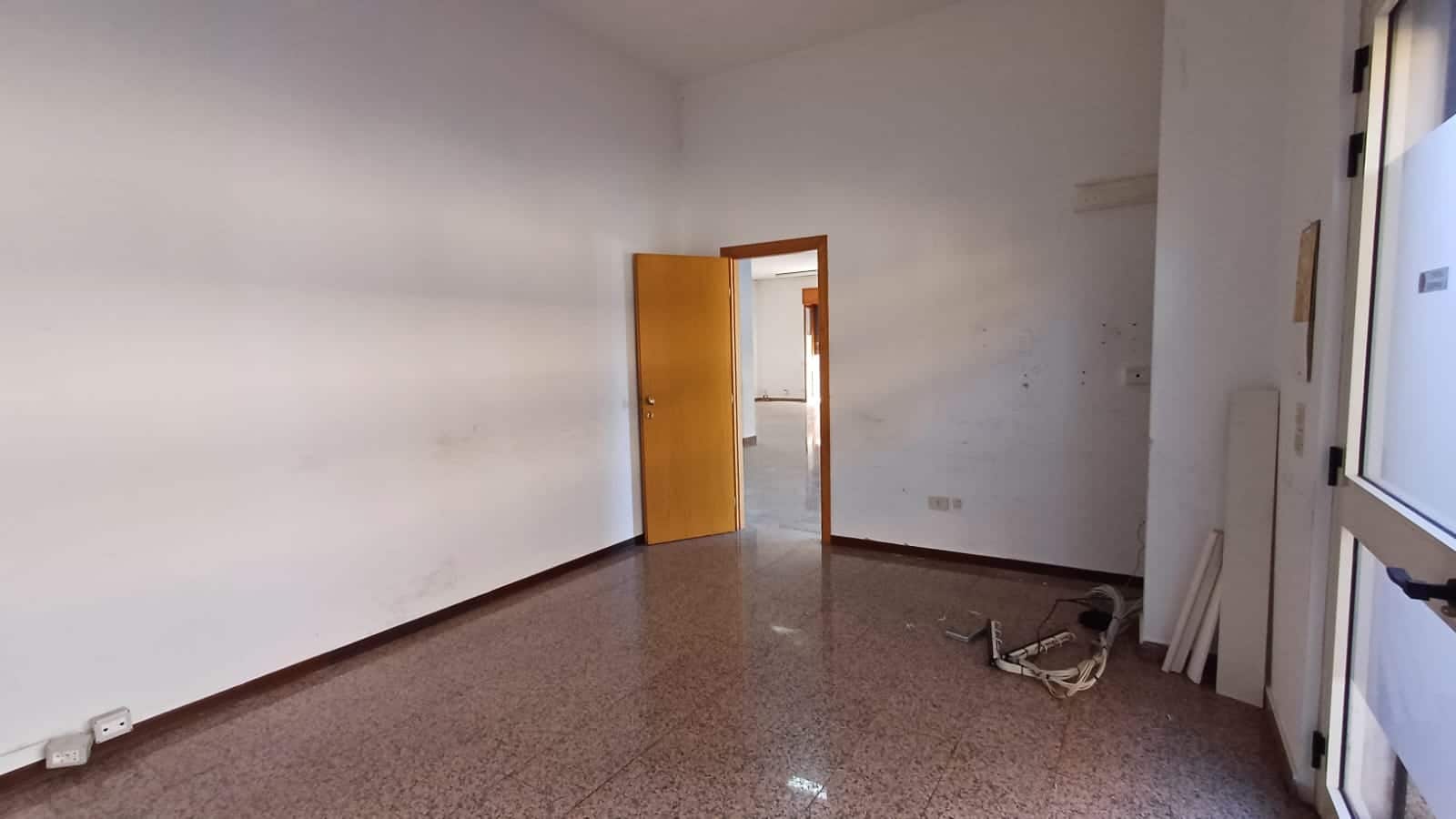 Finestra in una stanza vuota con pareti bianche, pavimento in marmo e porta in legno, pronta per ristrutturazione, ideale per investimento immobiliare.