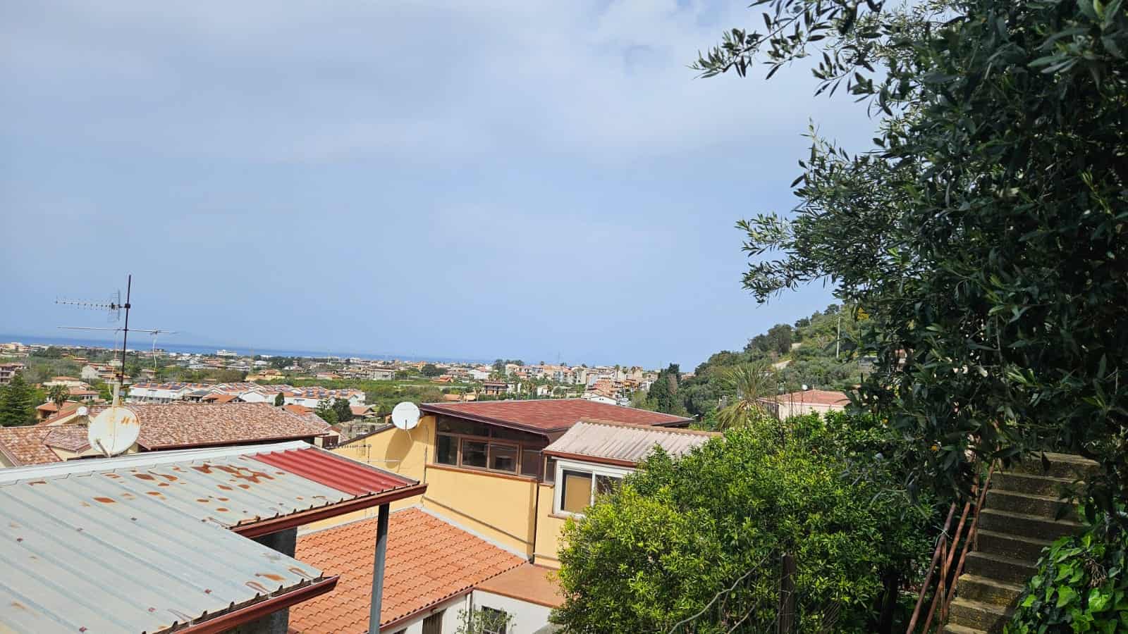 Vista panoramica delle case nel quartiere residenziale con vista mare, inclusi tetti in tetto e vegetazione rigogliosa, ideale per servizi immobiliari e immobili di lusso.