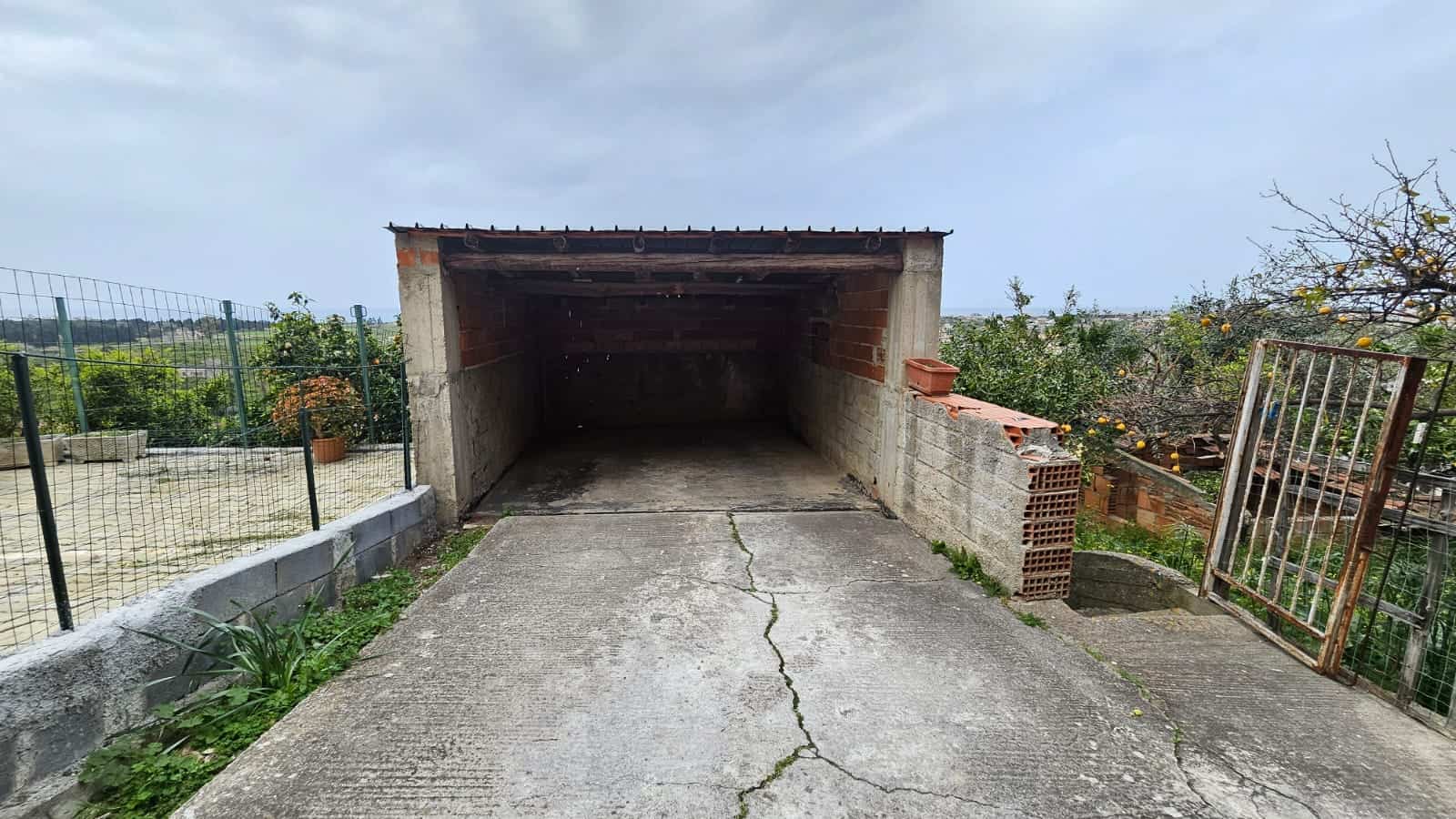 Garage rustico in pietra e mattoni con tetto in lamiera, spazioso e immerso nel verde, ottimo per posteggiare auto o come deposito all'aperto, in zona tranquilla e panoramica.