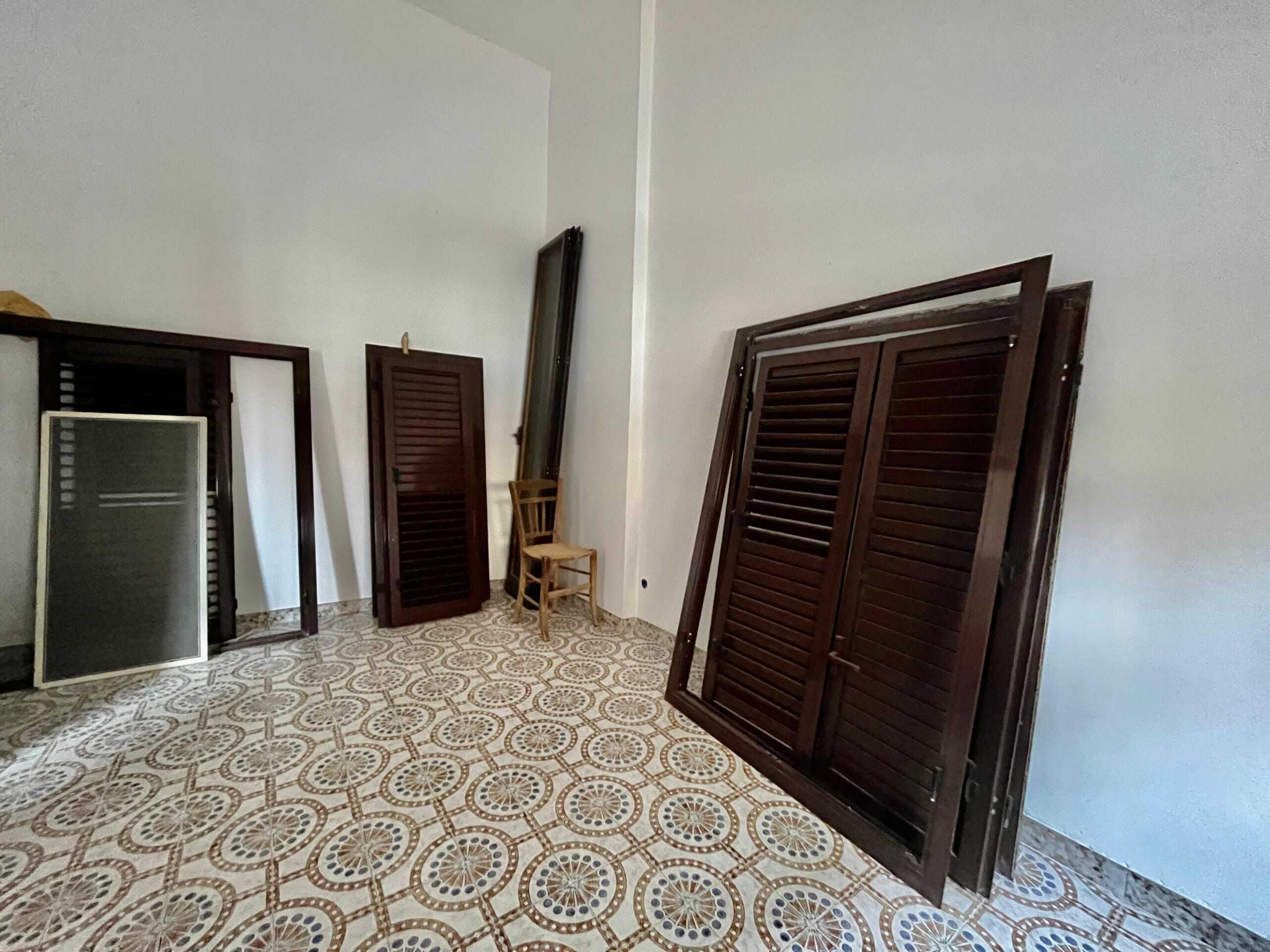 Sgombero armadi in legno folding, con dettagli classici, pronti per installazione o trasporto, in una stanza con pavimento decorato in ceramica.